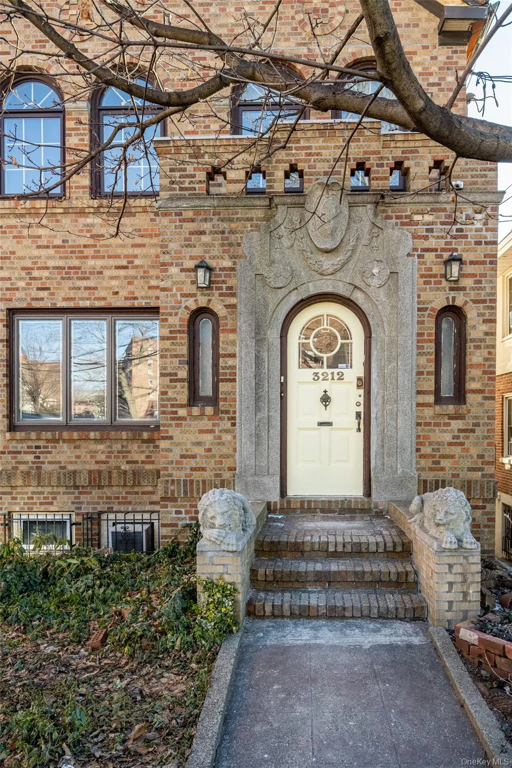 Brick facade with stone architectural detailing, arched entryway, and decorative window grilles Brick facade with stone architectural detailing, arched entryway, and decorative window grilles