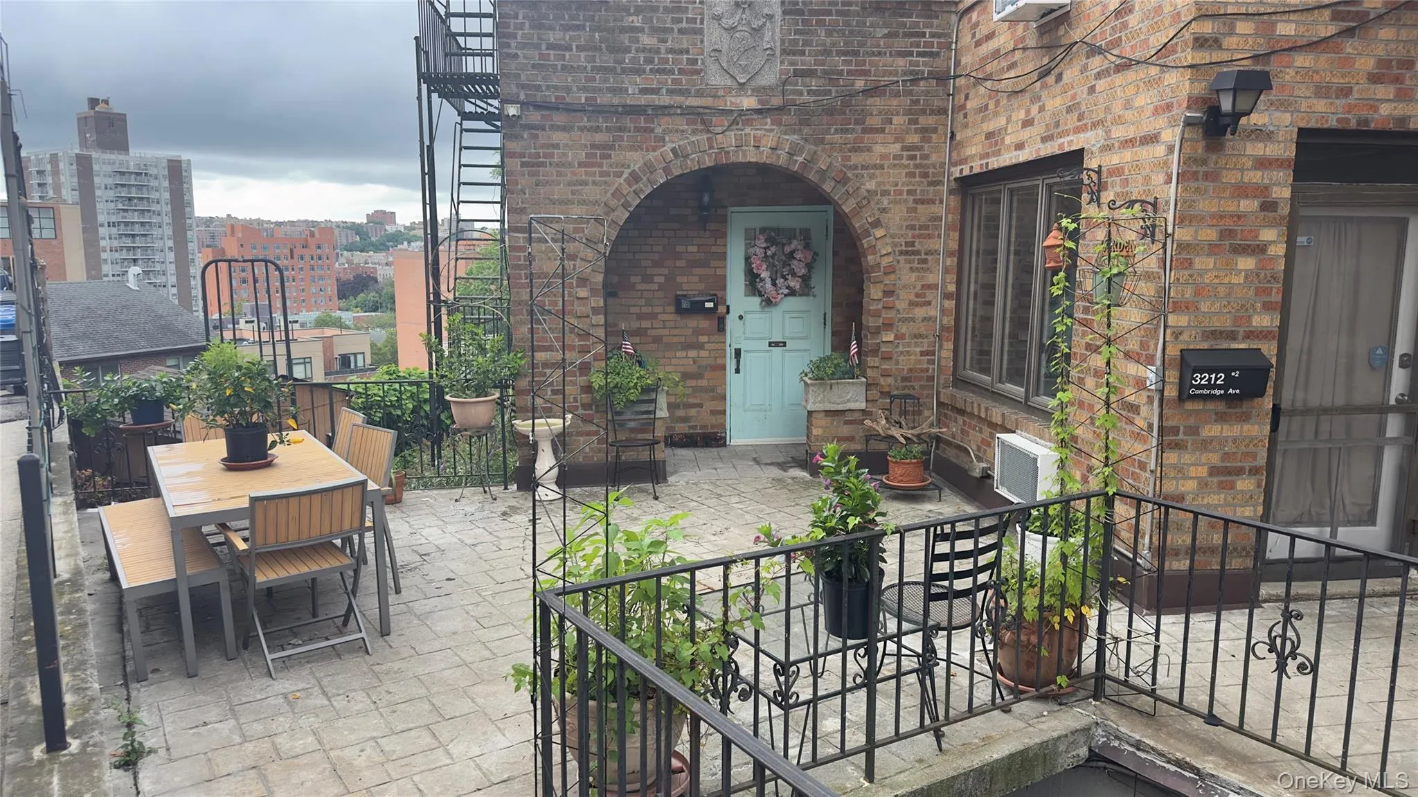 Spacious paved patio with wrought iron railings, featuring an arched brick entryway and a light blue door Spacious paved patio with wrought iron railings, featuring an arched brick entryway and a light blue door