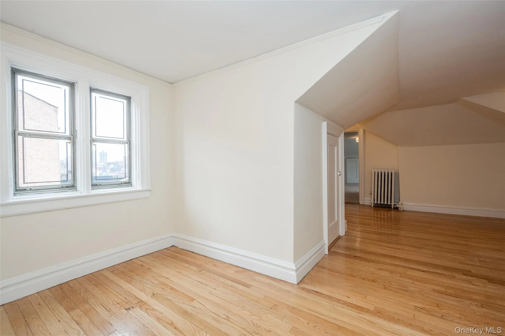 Home Office area with Hardwood flooring throughout featuring white trim, double sash windows, and a radiator Home Office area with Hardwood flooring throughout featuring white trim, double sash windows, and a radiator