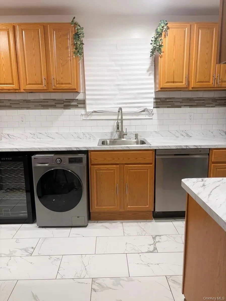 Kitchen featuring wood cabinetry, white subway tile backsplash, and light-toned countertops. Appliances. Kitchen featuring wood cabinetry, white subway tile backsplash, and light-toned countertops. Appliances.