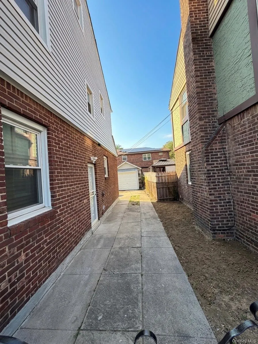 Paved walkway leading to a rear structure with white siding. Side door entrance. Paved walkway leading to a rear structure with white siding. Side door entrance.