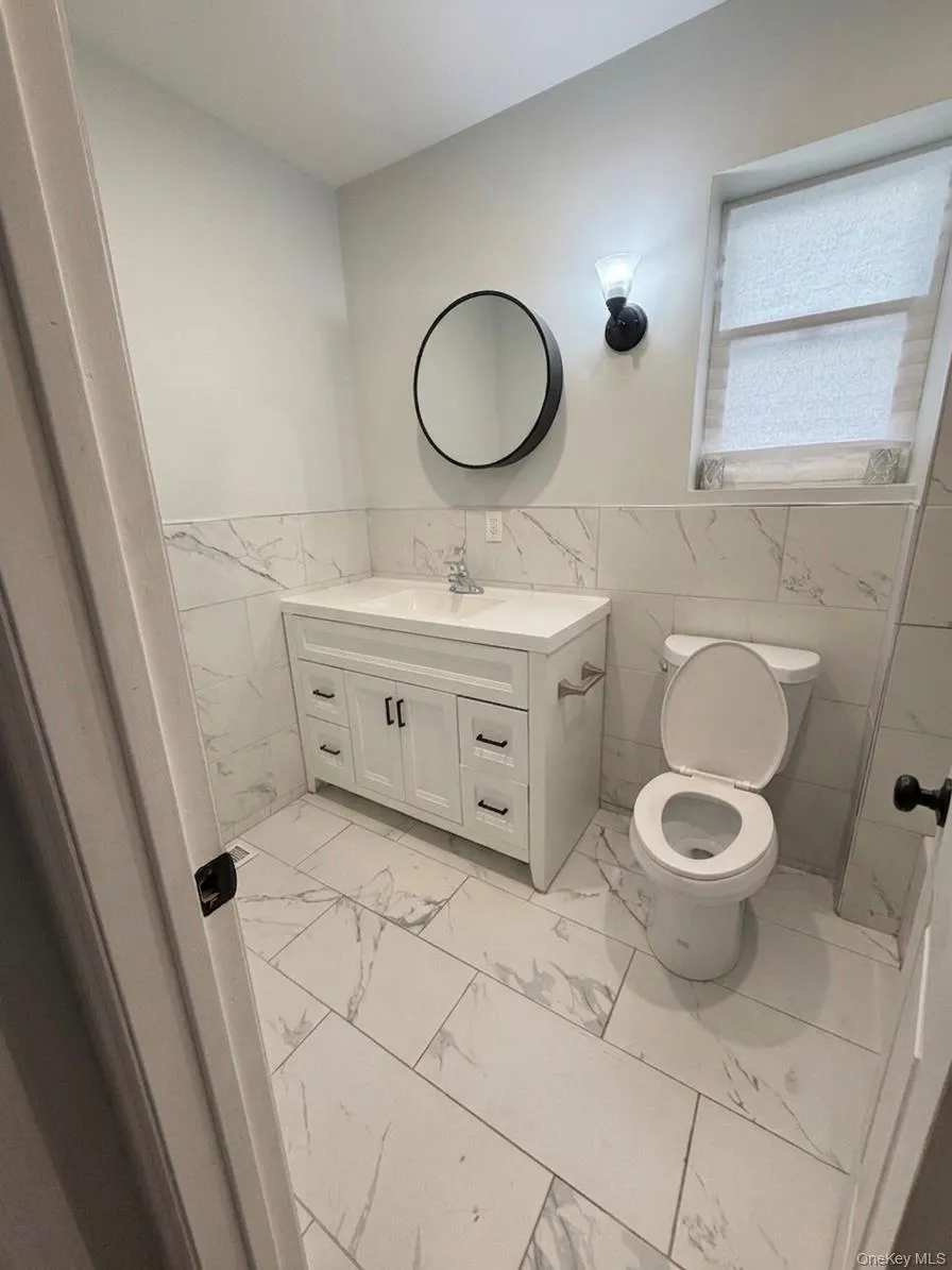 White vanity with integrated sink, black hardware, and a coordinating round mirror White vanity with integrated sink, black hardware, and a coordinating round mirror