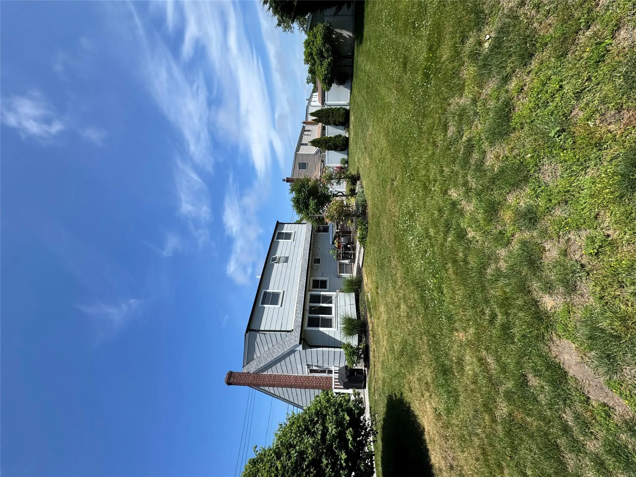 Expansive backyard featuring a large grass area, a patio space, and mature perimeter trees Expansive backyard featuring a large grass area, a patio space, and mature perimeter trees