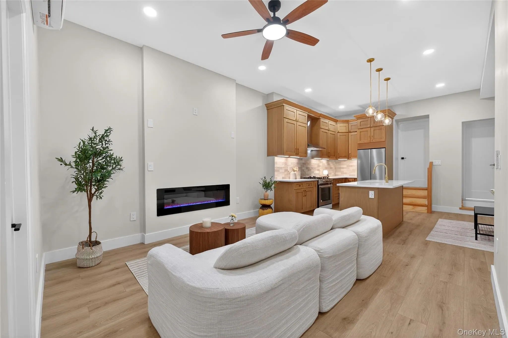 Open-concept living area featuring wood-finish flooring, a contemporary linear fireplace, and recessed lighting Open-concept living area featuring wood-finish flooring, a contemporary linear fireplace, and recessed lighting