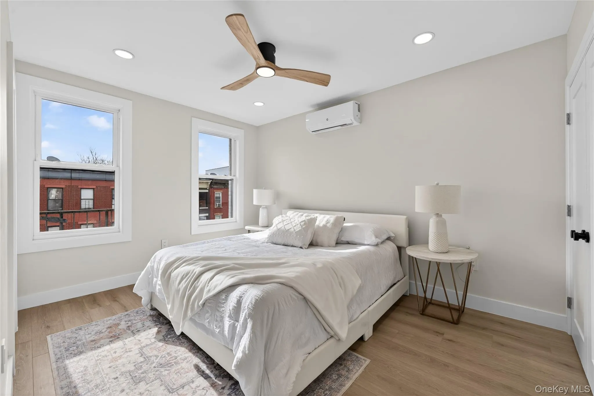 Bedroom featuring wood-finish flooring, two large windows, recessed ceiling lighting, and a modern ceiling fan Bedroom featuring wood-finish flooring, two large windows, recessed ceiling lighting, and a modern ceiling fan