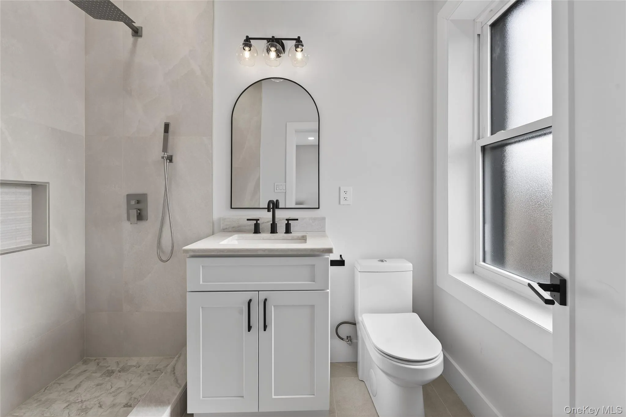Modern bathroom featuring a white vanity with a rectangular sink, matte black faucet, and an arched mirror Modern bathroom featuring a white vanity with a rectangular sink, matte black faucet, and an arched mirror