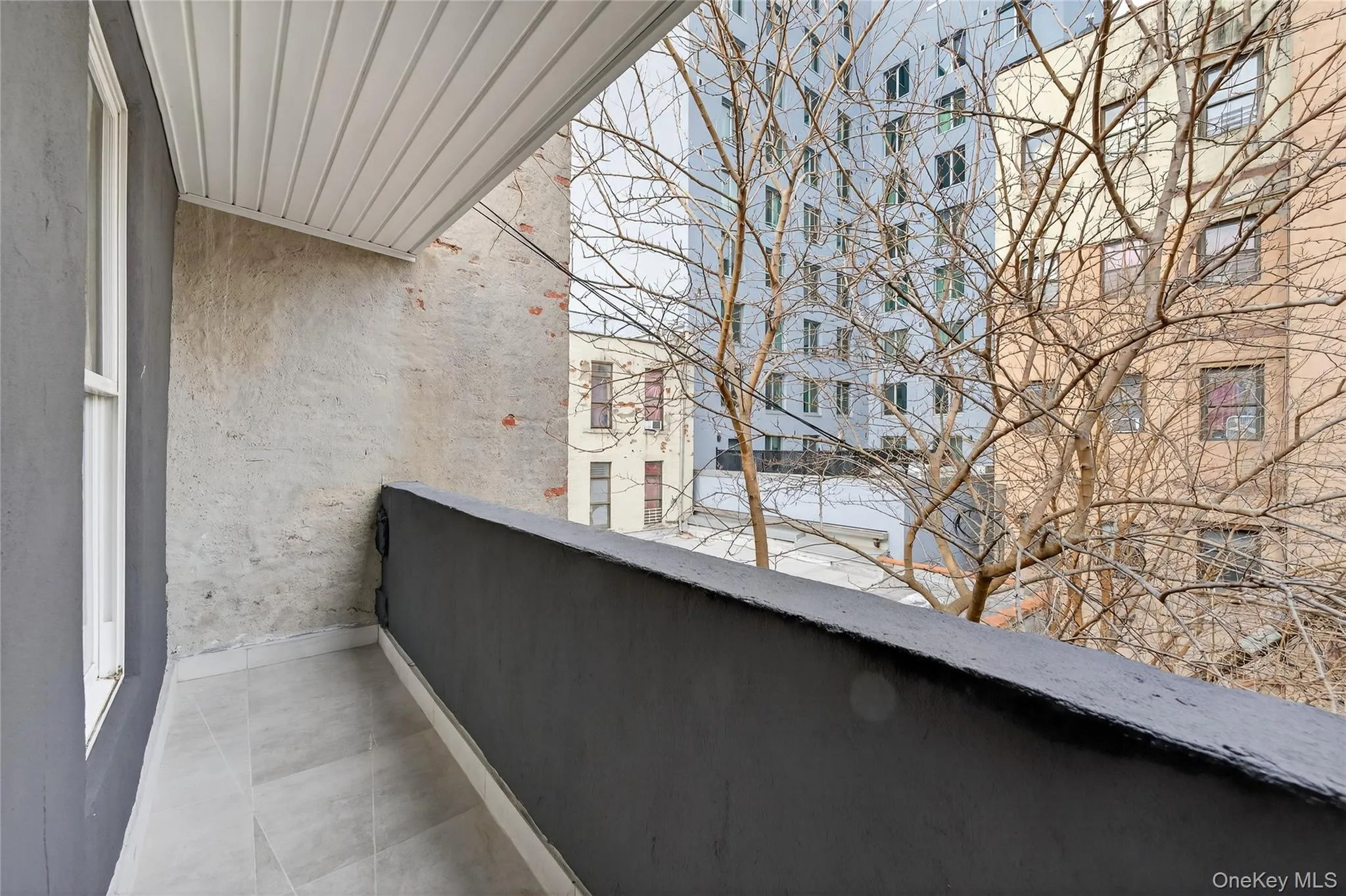 Private balcony featuring contemporary gray tile flooring, a dark gray painted railing, and a white paneled ceiling Private balcony featuring contemporary gray tile flooring, a dark gray painted railing, and a white paneled ceiling