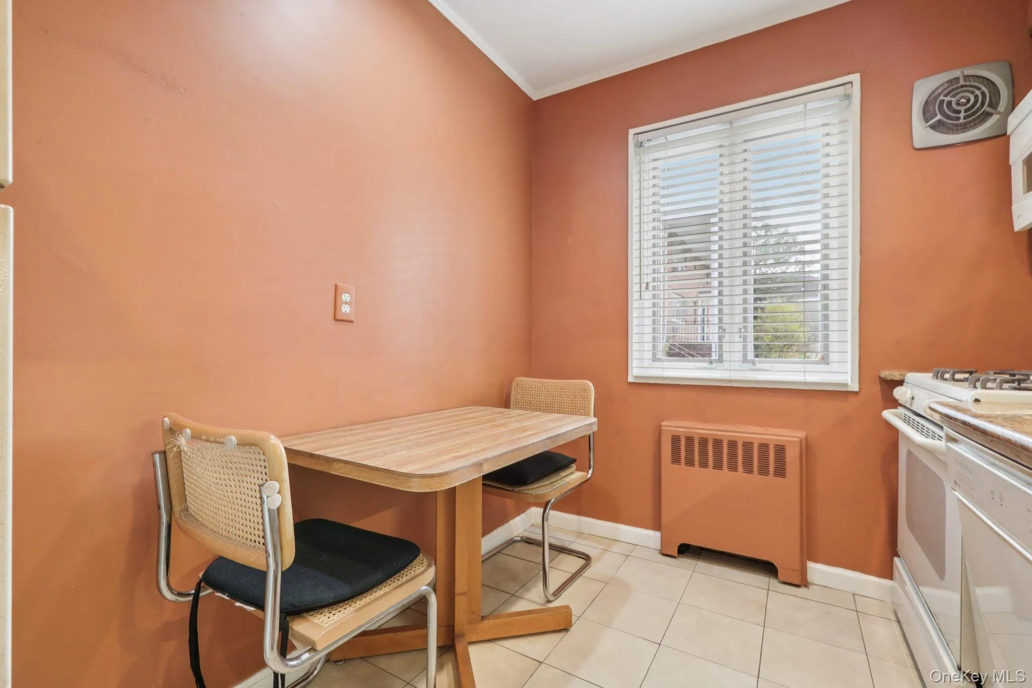 Dining space featuring radiator heating unit, light tile patterned floors, and ornamental molding Dining space featuring radiator heating unit, light tile patterned floors, and ornamental molding
