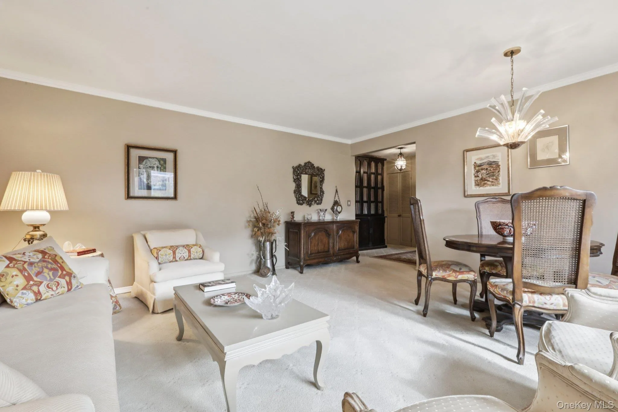 Carpeted living area with ornamental molding and a chandelier Carpeted living area with ornamental molding and a chandelier