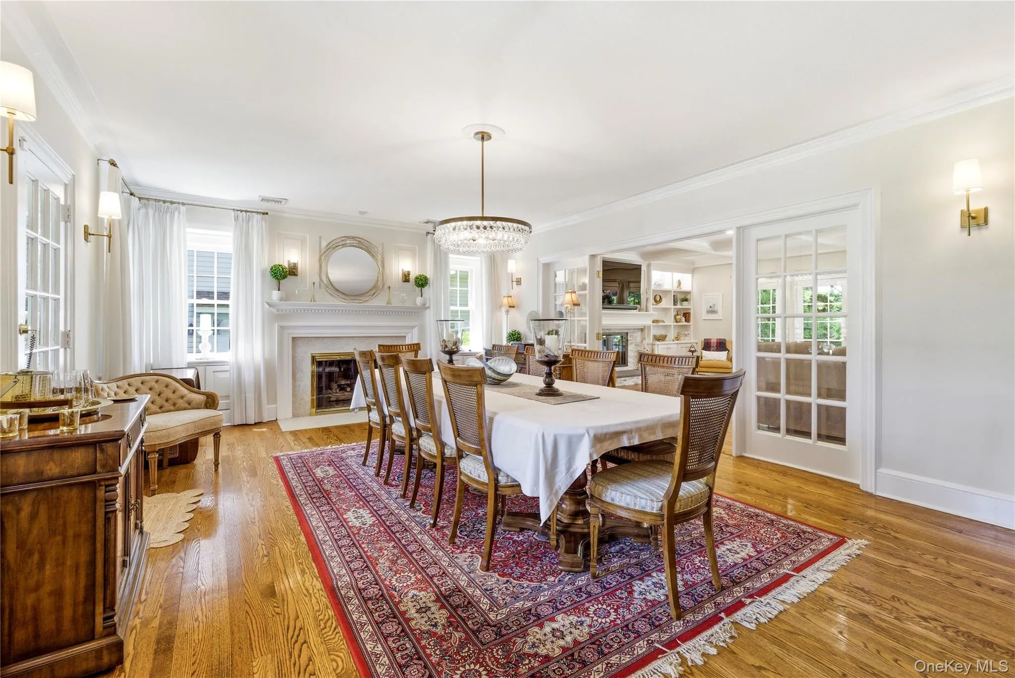 Formal dining space featuring hardwood flooring, a fireplace with a detailed mantel, and a crystal chandelier Formal dining space featuring hardwood flooring, a fireplace with a detailed mantel, and a crystal chandelier