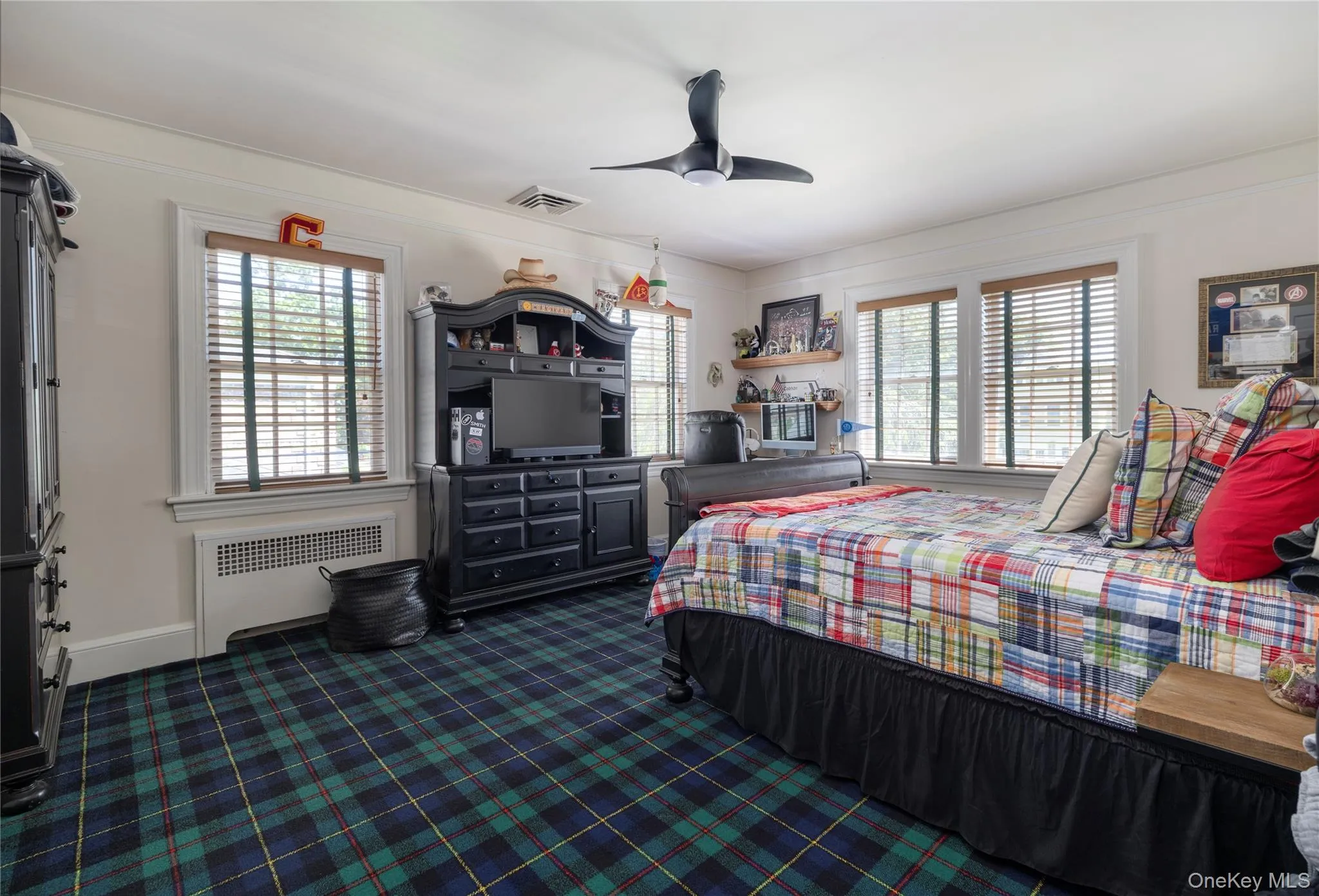Interior room featuring tartan-patterned carpeting, multiple windows with blinds, a ceiling fan, and white trim Interior room featuring tartan-patterned carpeting, multiple windows with blinds, a ceiling fan, and white trim
