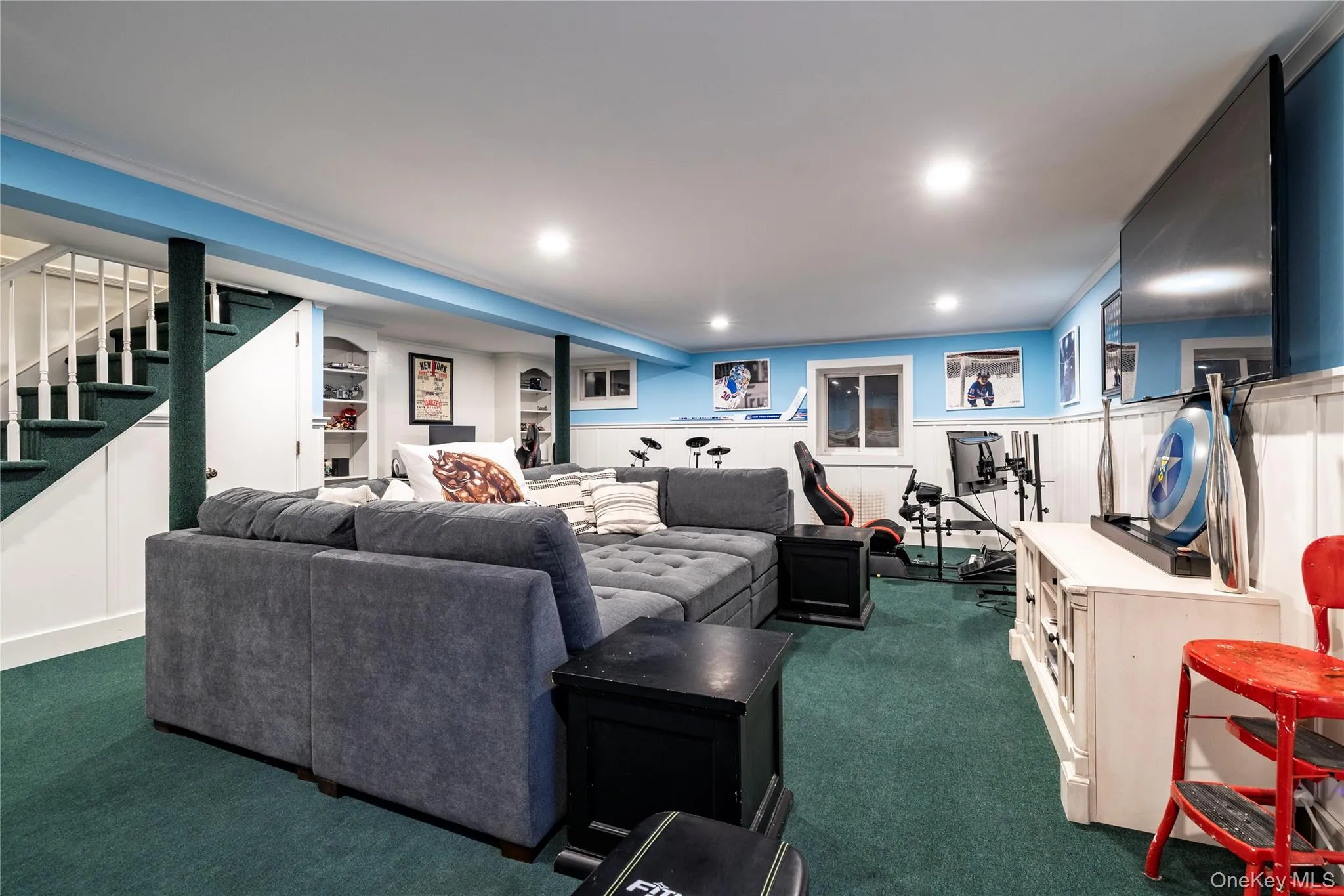 Finished recreation room featuring recessed lighting, a carpeted floor, white wainscoting, and a built-in entertainment center Finished recreation room featuring recessed lighting, a carpeted floor, white wainscoting, and a built-in entertainment center