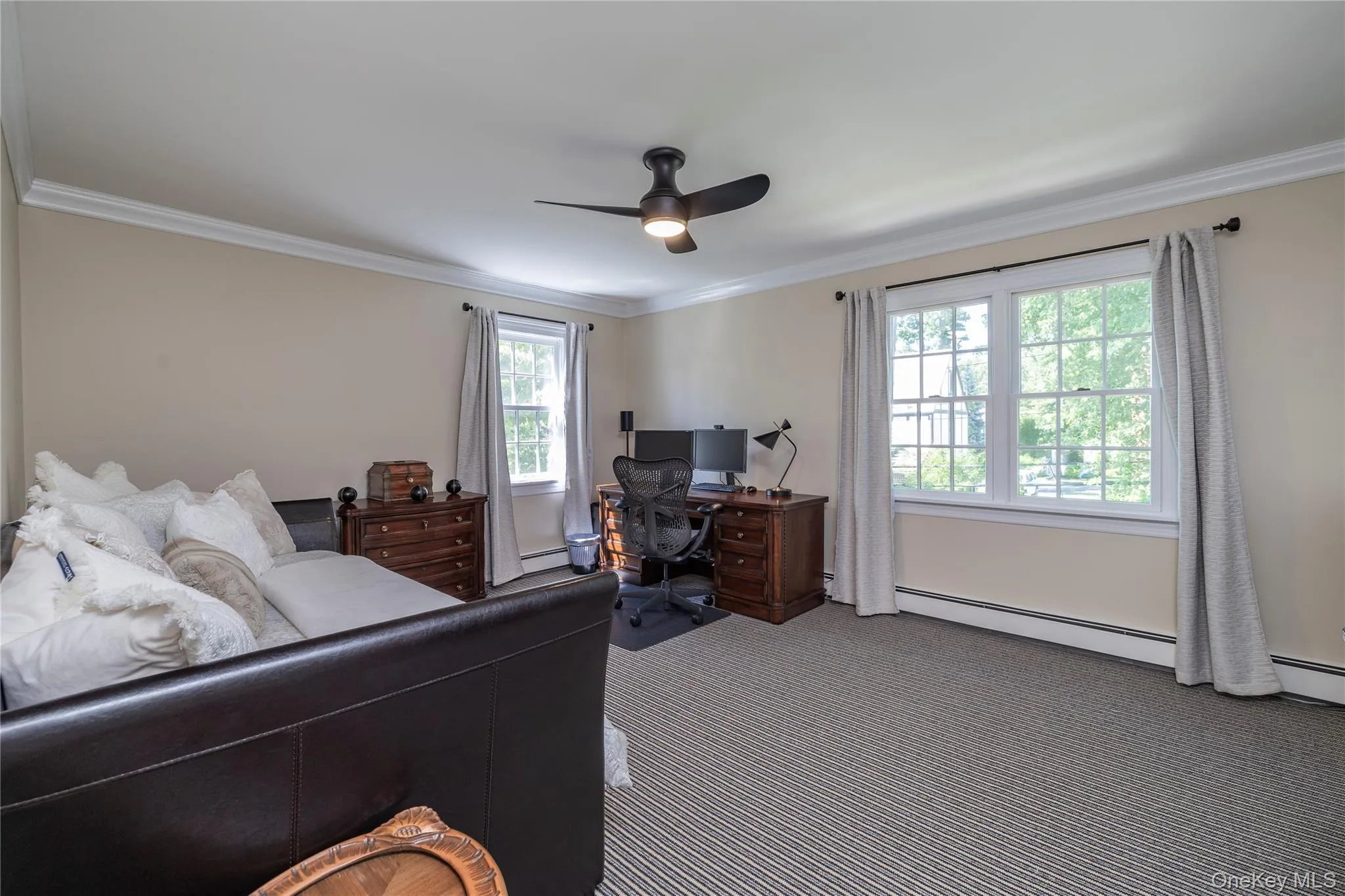 Spacious room featuring neutral painted walls, crown molding, a ceiling fan with light, and two large windows with white trim Spacious room featuring neutral painted walls, crown molding, a ceiling fan with light, and two large windows with white trim