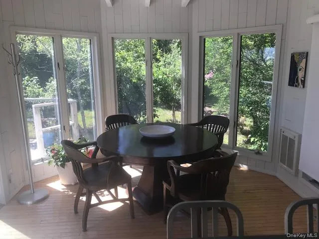 Sunroom featuring wood-type flooring, a wooden deck, wooden walls, and plenty of natural light Sunroom featuring wood-type flooring, a wooden deck, wooden walls, and plenty of natural light