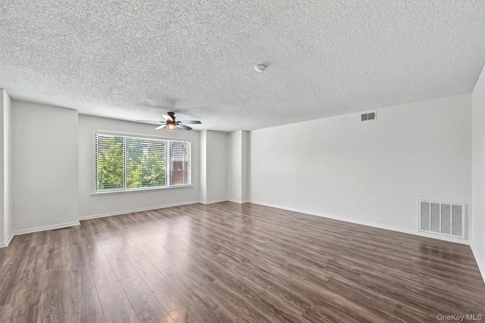 Large open concept living room and dining room with oversized window overlooking the courtyard. Large open concept living room and dining room with oversized window overlooking the courtyard.