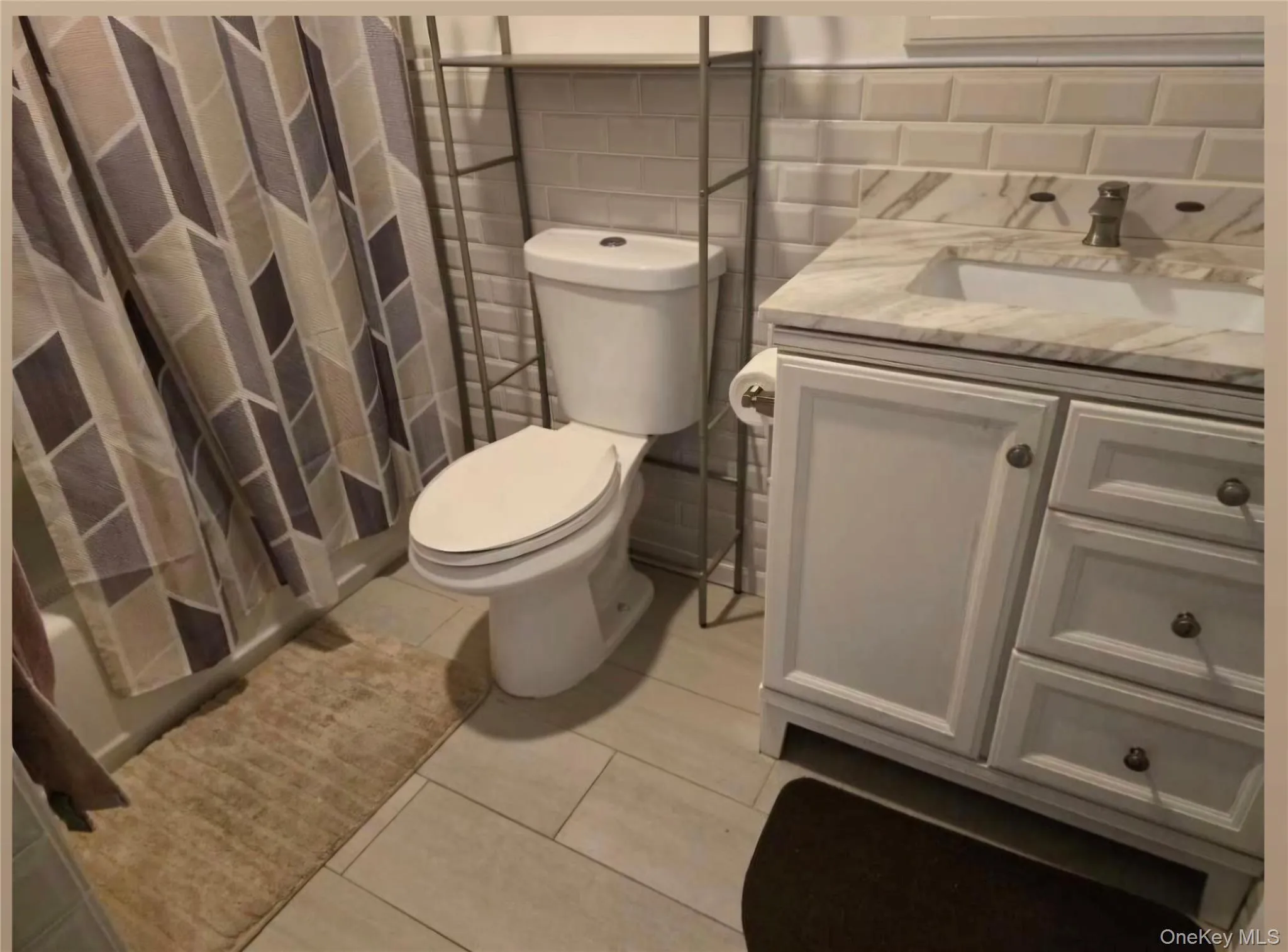 Digitally removed personal items Bathroom featuring a single vanity with a stone countertop, tiled floor, tiled backsplash tiled shower and an integrated sink Digitally removed personal items Bathroom featuring a single vanity with a stone countertop, tiled floor, tiled backsplash tiled shower and an integrated sink
