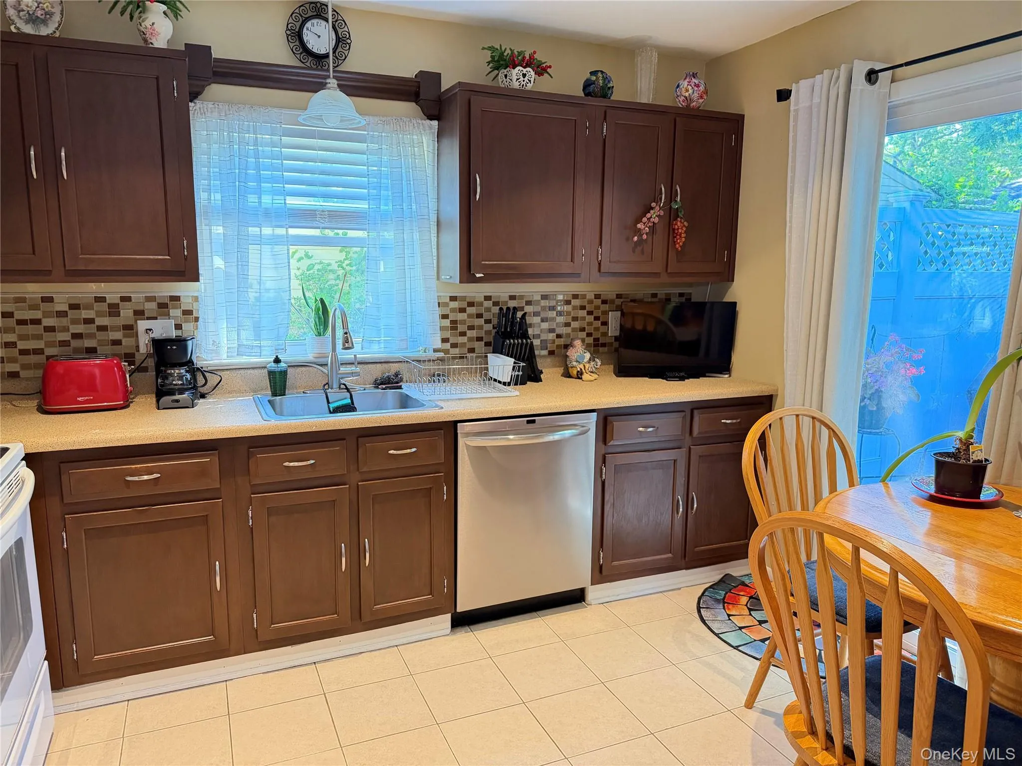 Compact kitchen area with dark wood-finish cabinetry and light-toned countertops Digitally removed personal items. Compact kitchen area with dark wood-finish cabinetry and light-toned countertops Digitally removed personal items.