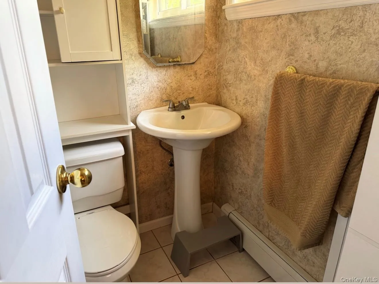 Pedestal sink with chrome-finish faucet, ceramic tile flooring, and integrated white cabinetry over the toilet. Digitally removed personal items Pedestal sink with chrome-finish faucet, ceramic tile flooring, and integrated white cabinetry over the toilet. Digitally removed personal items