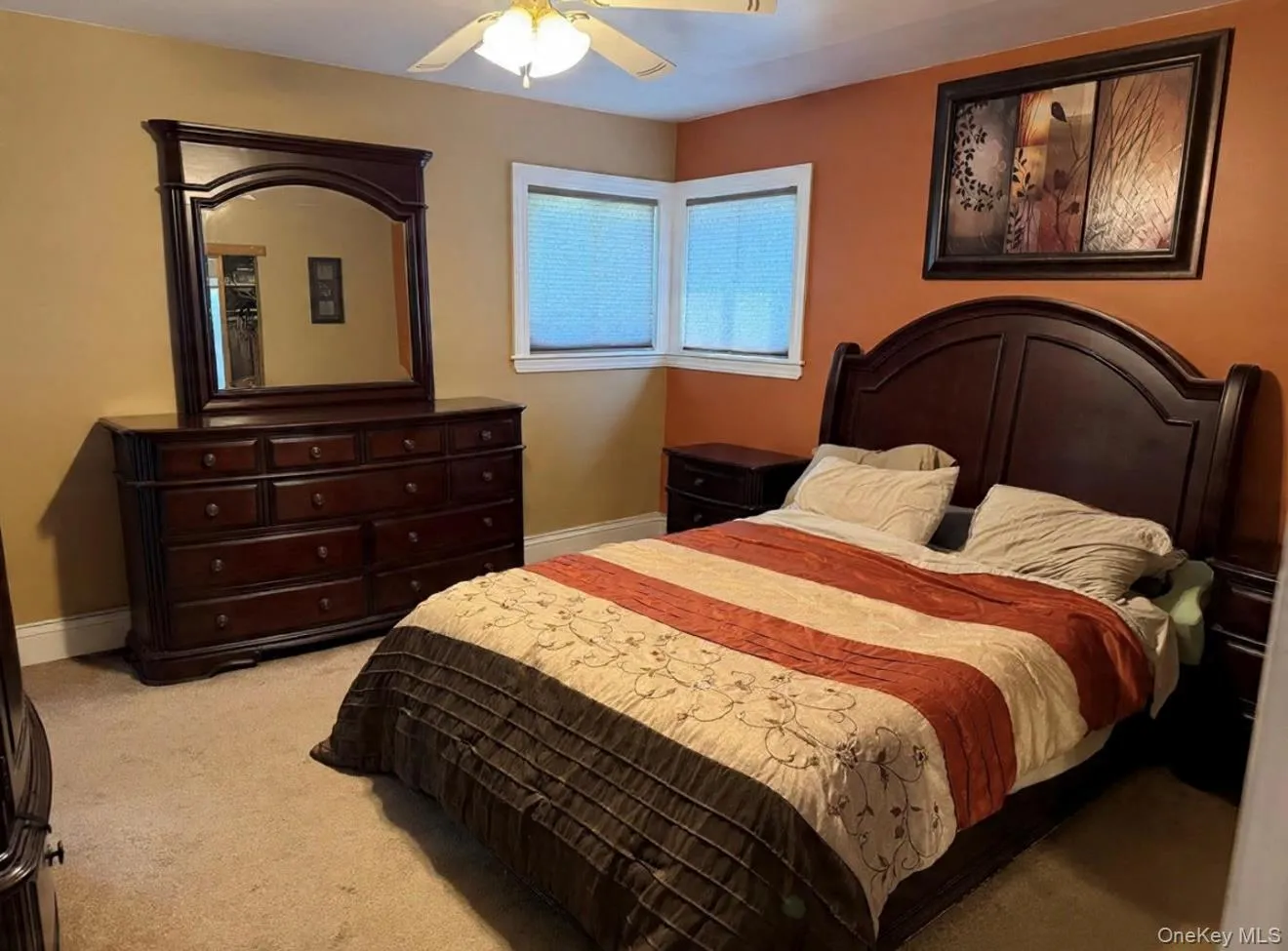 Carpeted room featuring a ceiling fan with integrated lighting, corner windows, and a two-tone wall treatment. Digitally removed personal items Carpeted room featuring a ceiling fan with integrated lighting, corner windows, and a two-tone wall treatment. Digitally removed personal items