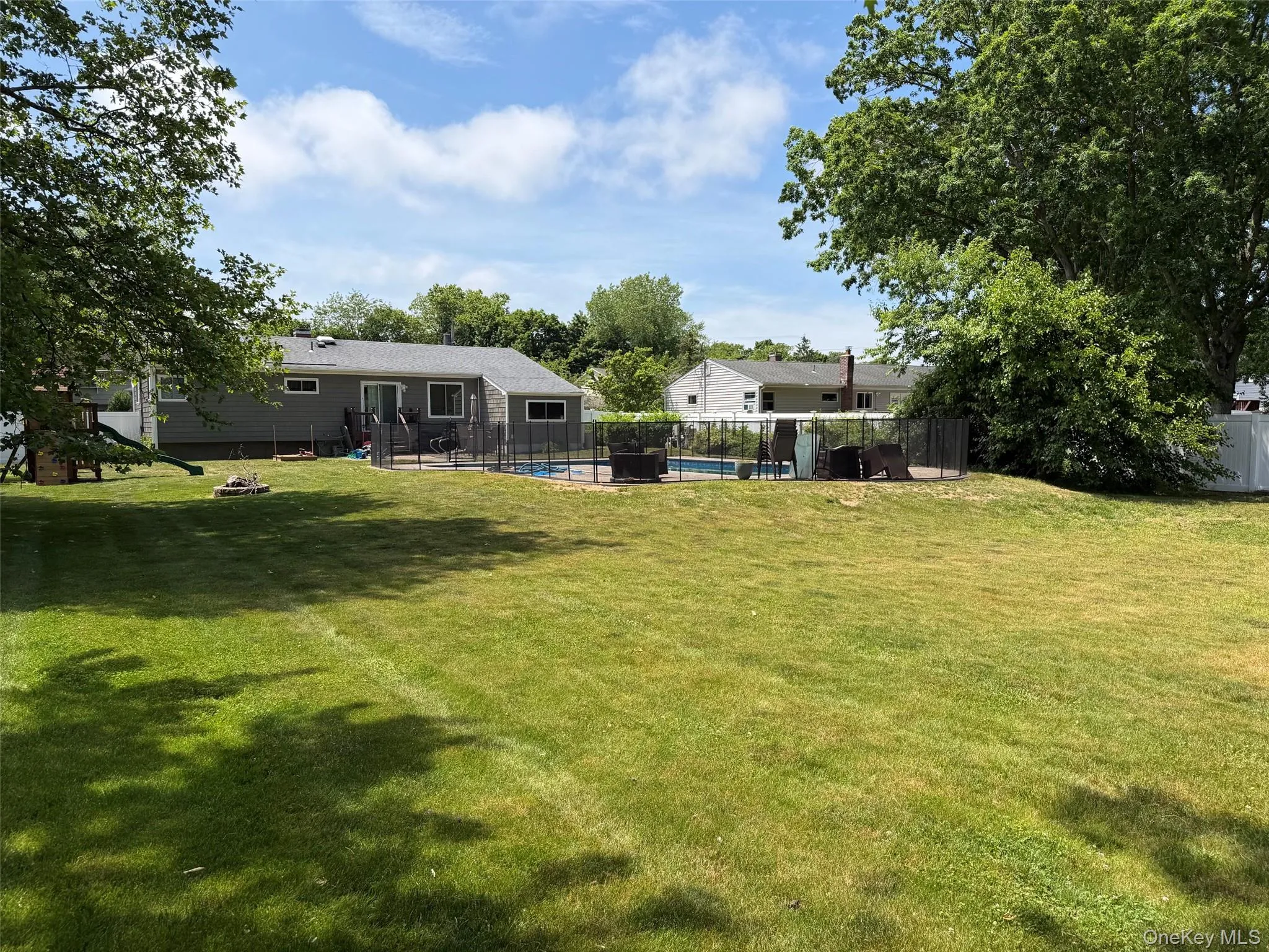 Expansive rear yard featuring a large lawn, mature trees, and a fenced in-ground swimming pool Expansive rear yard featuring a large lawn, mature trees, and a fenced in-ground swimming pool