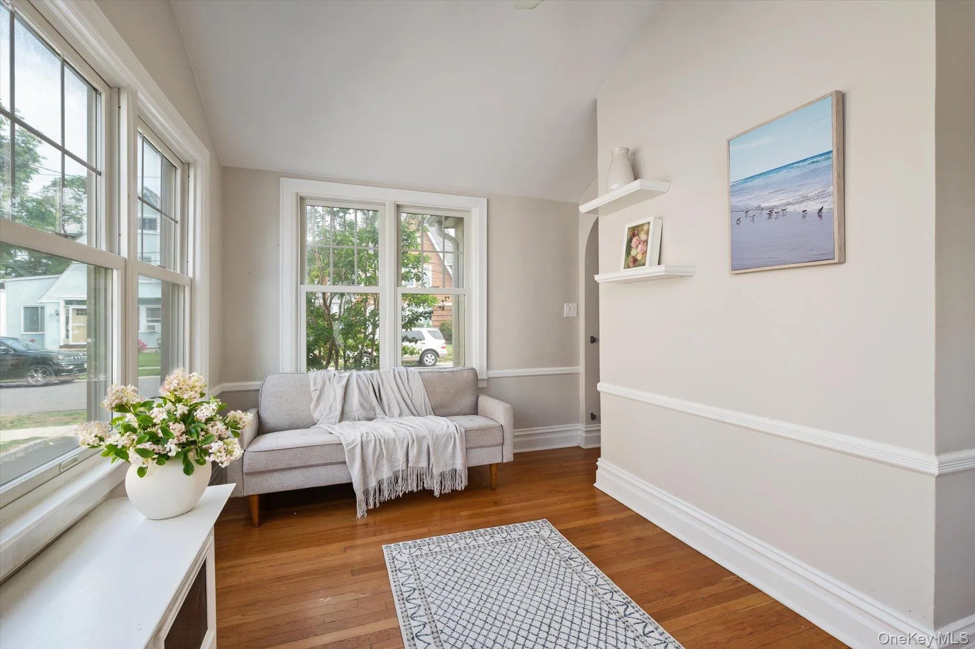 Light-filled interior space featuring wood-finish flooring, white baseboards, and chair rail molding Light-filled interior space featuring wood-finish flooring, white baseboards, and chair rail molding