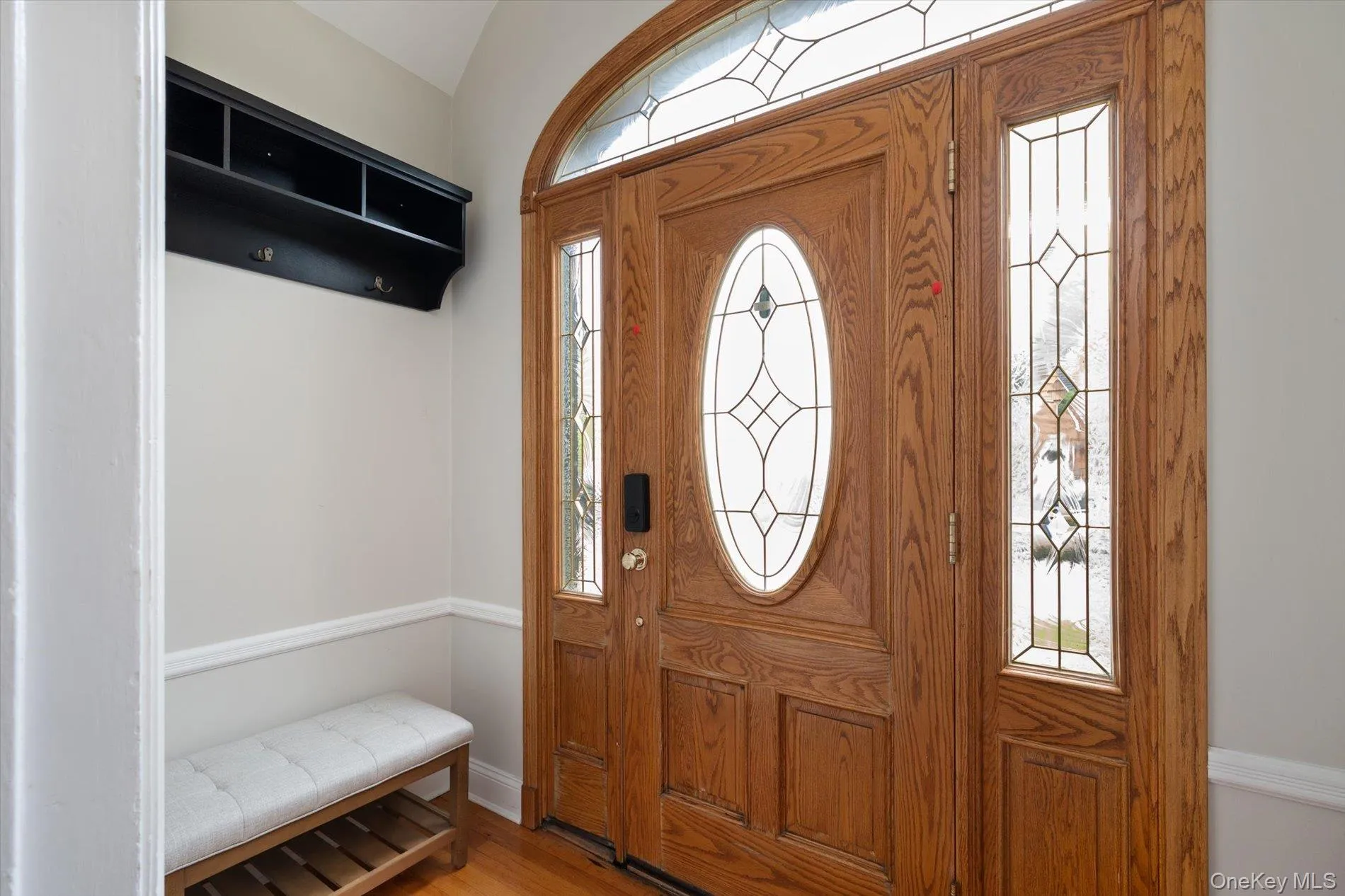 Wood-finish entry door with oval leaded glass insert, flanked by sidelight panels and topped with an arched transom window Wood-finish entry door with oval leaded glass insert, flanked by sidelight panels and topped with an arched transom window