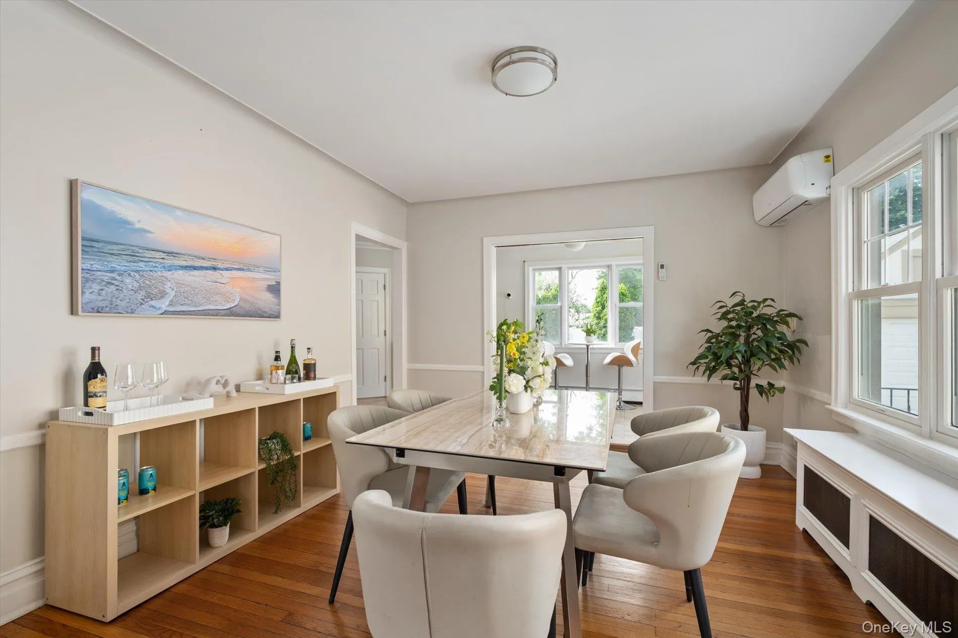 Hardwood flooring throughout, featuring a dining area with a rectangular table, and a built-in shelving unit Hardwood flooring throughout, featuring a dining area with a rectangular table, and a built-in shelving unit