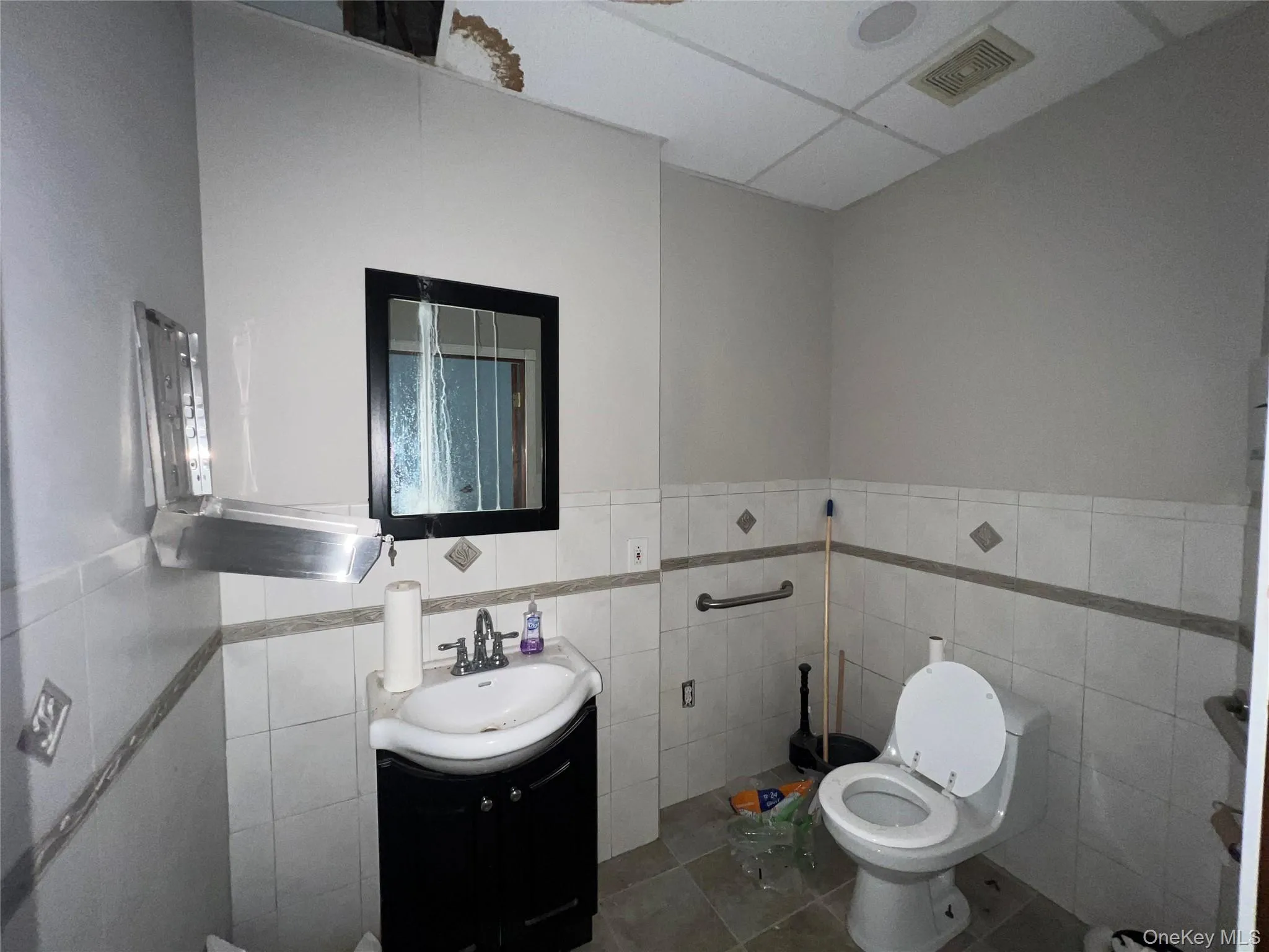 Bathroom with tile walls, vanity, wainscoting, and tile patterned floors Bathroom with tile walls, vanity, wainscoting, and tile patterned floors