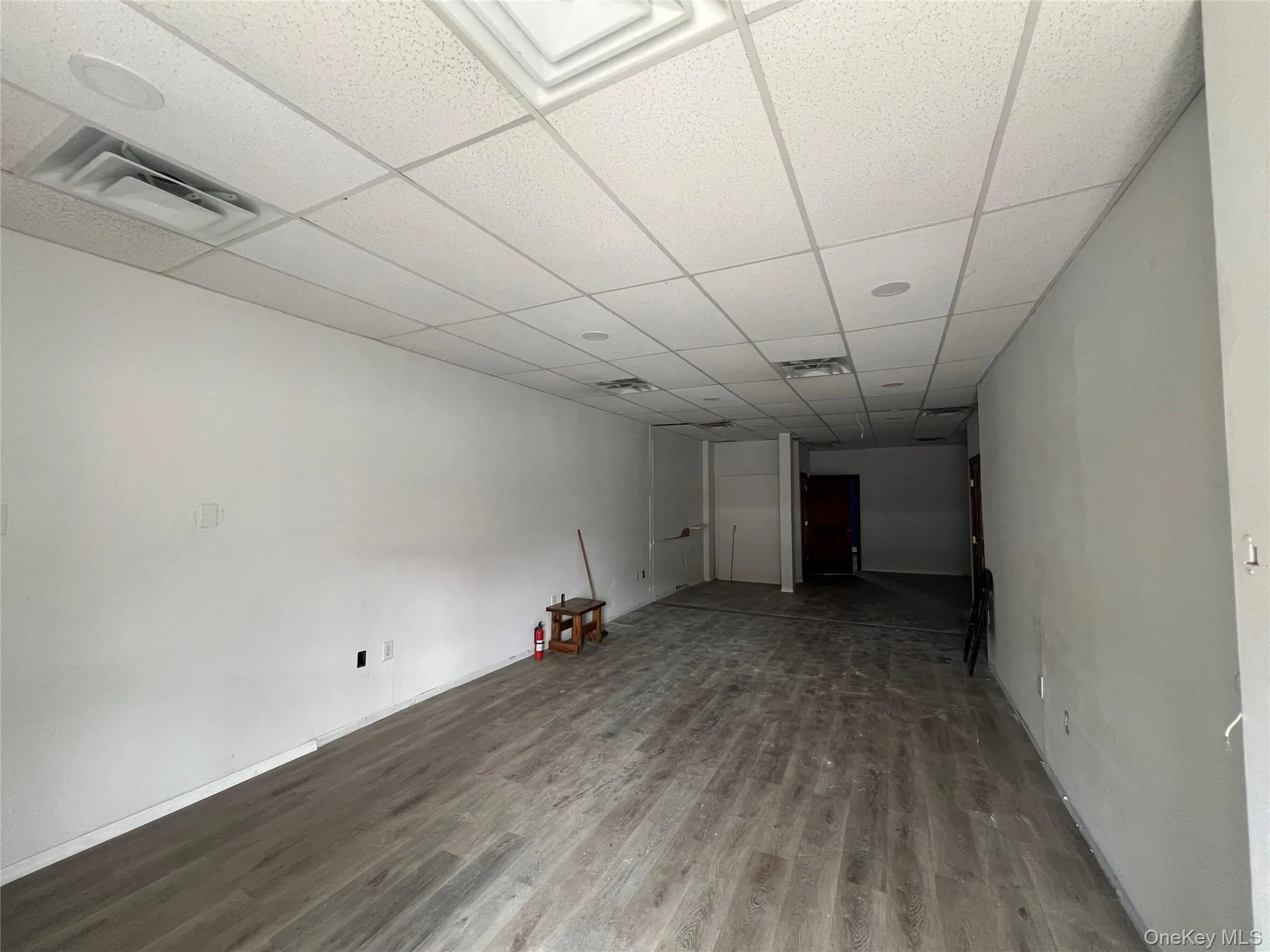 Unfurnished room with wood finished floors and a paneled ceiling Unfurnished room with wood finished floors and a paneled ceiling