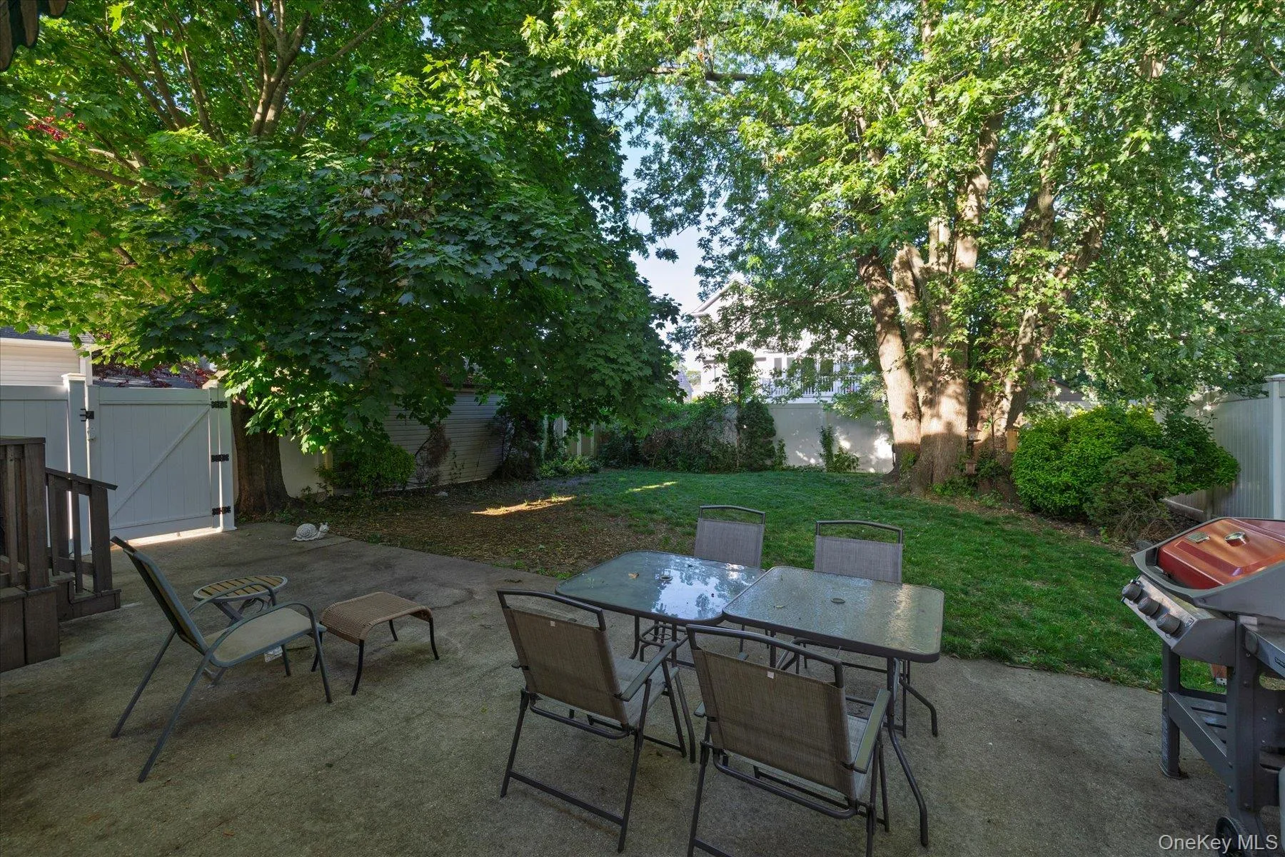 Expansive patio with green lawn and trees providing shade Expansive patio with green lawn and trees providing shade