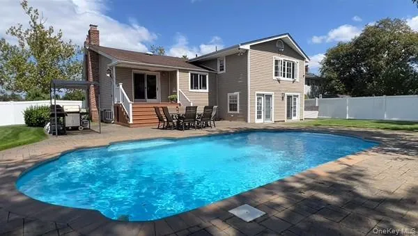Outdoor swimming pool with a surrounding paver patio and a neutral-toned siding exterior Outdoor swimming pool with a surrounding paver patio and a neutral-toned siding exterior