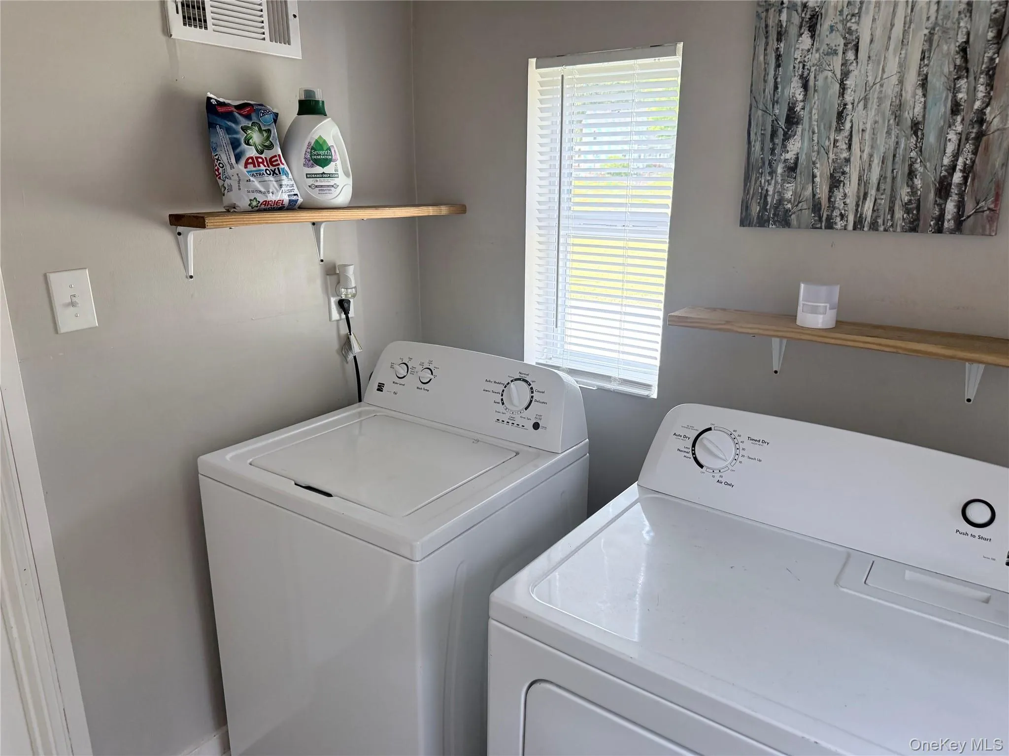 Dedicated laundry area featuring a window, built-in shelving, and light gray wall paint Dedicated laundry area featuring a window, built-in shelving, and light gray wall paint