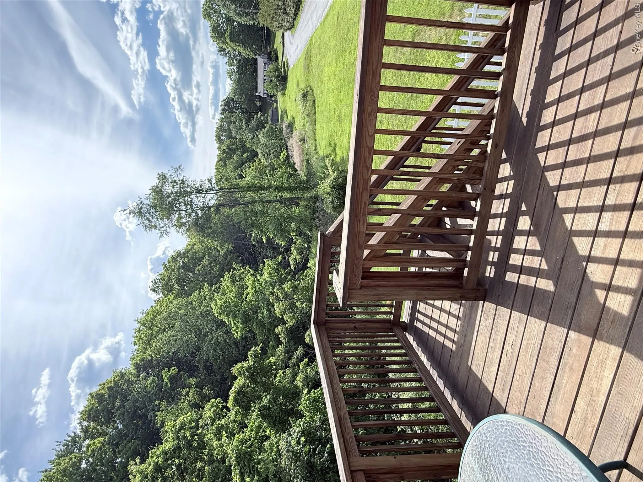 Expansive wood deck with natural wood railings overlooking a verdant landscape Expansive wood deck with natural wood railings overlooking a verdant landscape