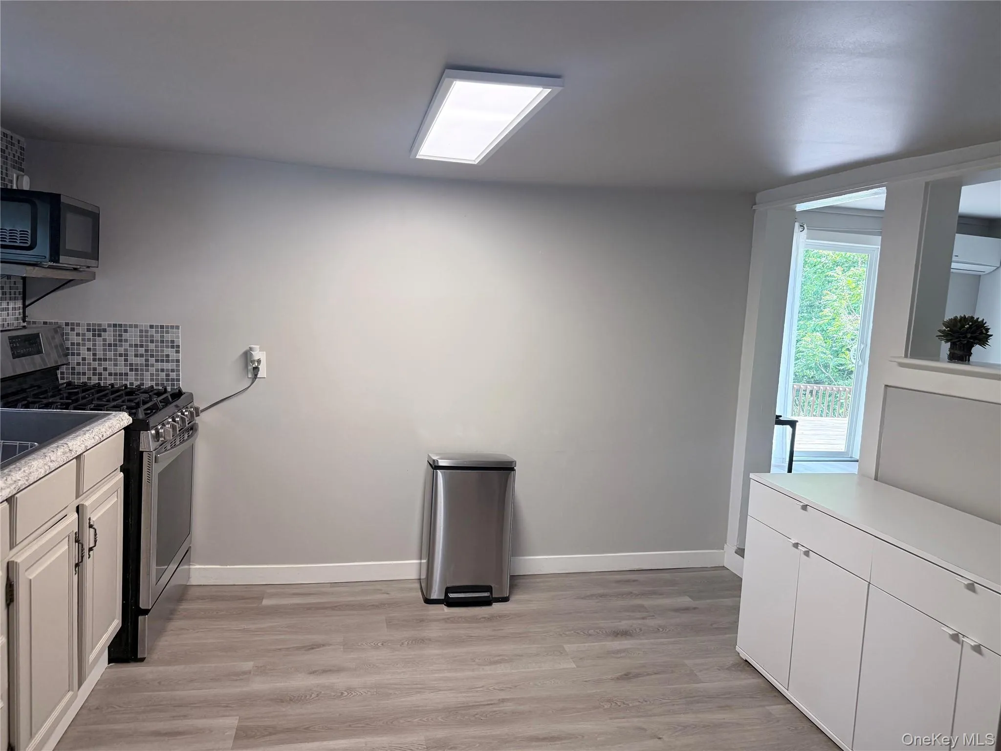Modern kitchen space featuring wood-finish flooring and a contemporary linear ceiling light Modern kitchen space featuring wood-finish flooring and a contemporary linear ceiling light