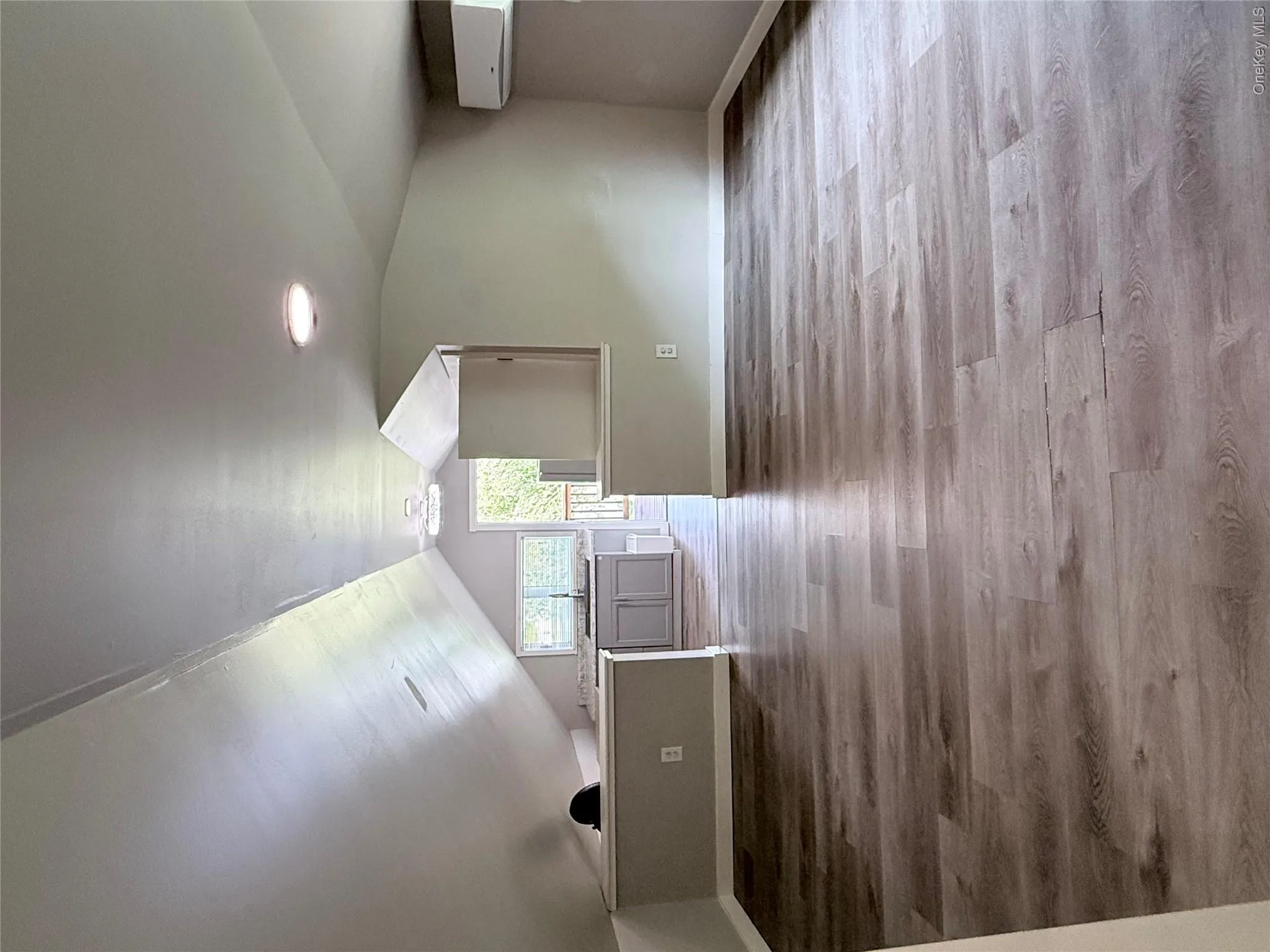 Spacious room featuring wood-finish flooring, vaulted ceilings, and recessed lighting Spacious room featuring wood-finish flooring, vaulted ceilings, and recessed lighting
