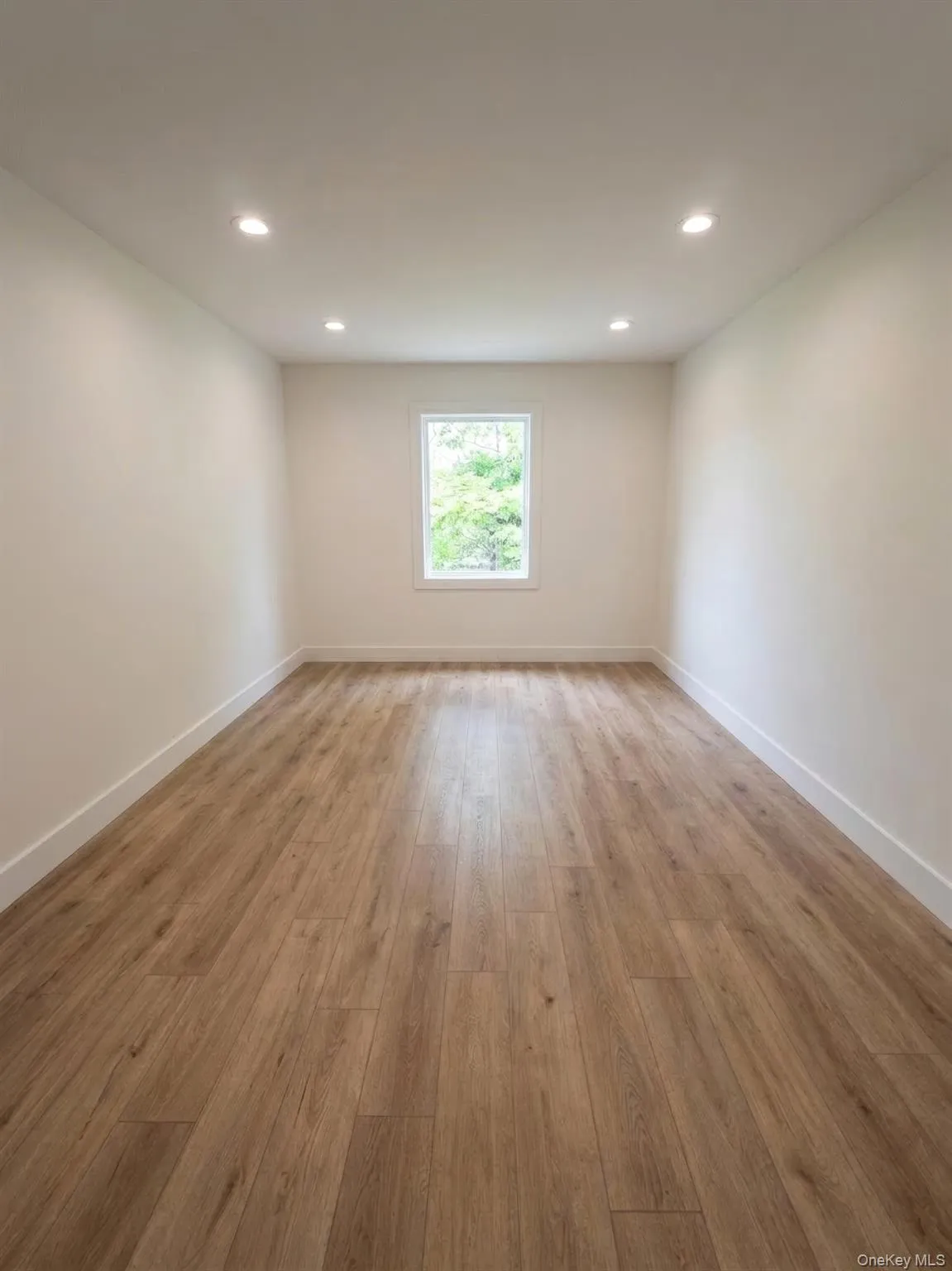 Bright room featuring finish flooring, white baseboards, a single window, recessed lighting, and light toned walls Bright room featuring finish flooring, white baseboards, a single window, recessed lighting, and light toned walls