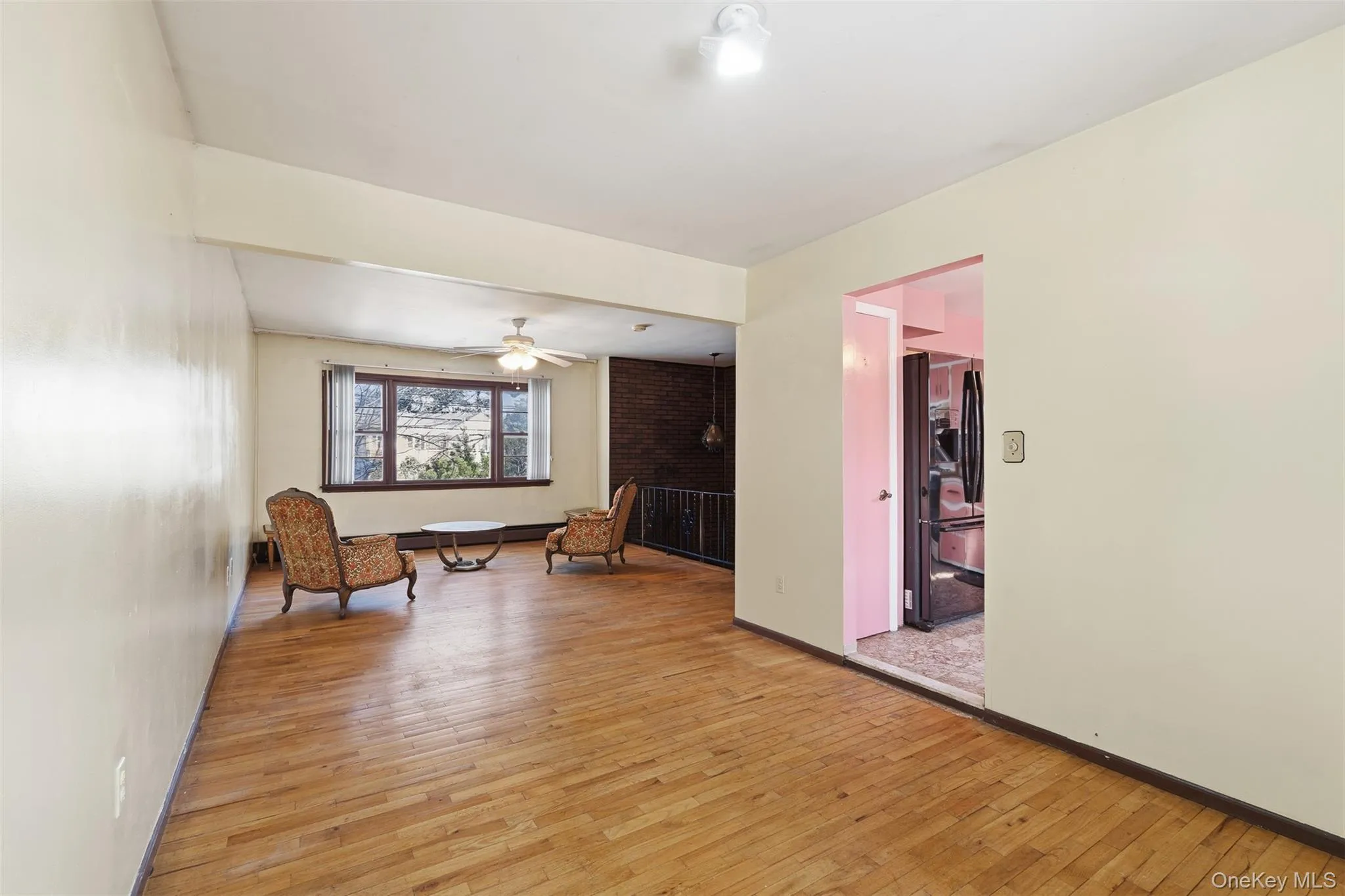 Spacious room featuring wood-finish flooring, a ceiling fan, and a large window with exterior views Spacious room featuring wood-finish flooring, a ceiling fan, and a large window with exterior views