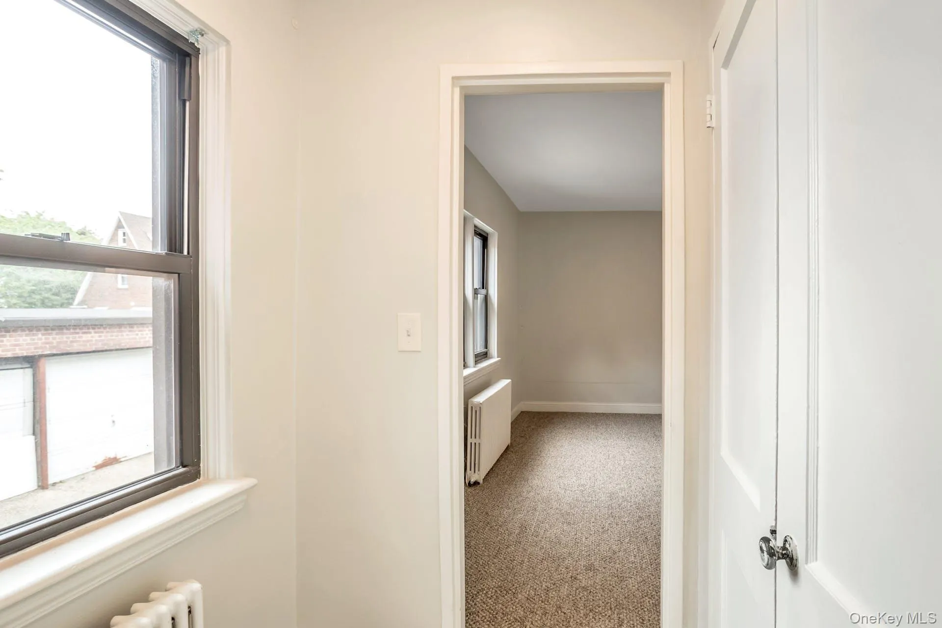 Hallway with radiator, carpet, and a healthy amount of sunlight Hallway with radiator, carpet, and a healthy amount of sunlight