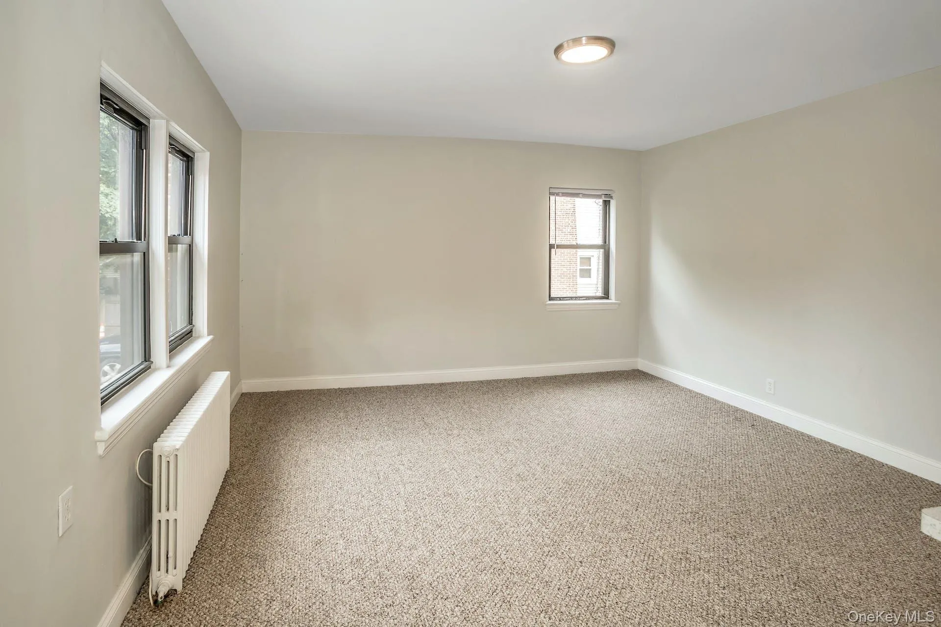 Unfurnished room featuring radiator heating unit, carpet, and baseboards Unfurnished room featuring radiator heating unit, carpet, and baseboards