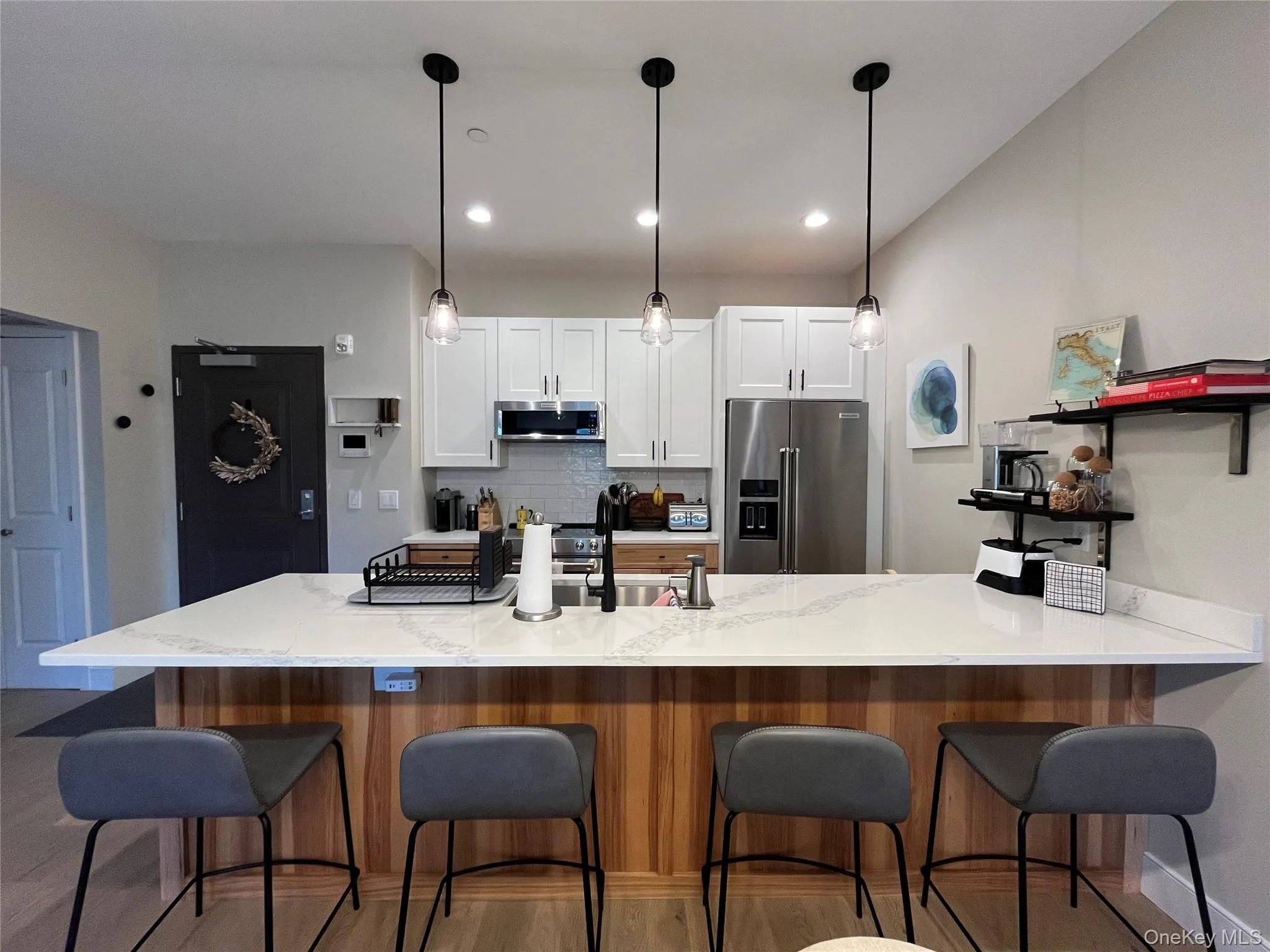 Kitchen island featuring a granite countertop, wood-finish paneling, and three pendant lights Kitchen island featuring a granite countertop, wood-finish paneling, and three pendant lights