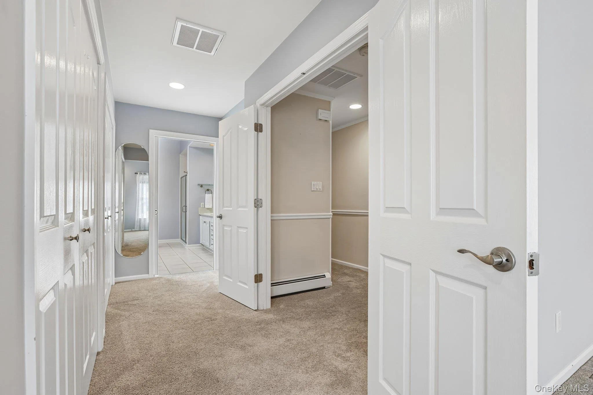 Hallway in primary bedroom suite with closets on the left, primary bath straight ahead. Hallway in primary bedroom suite with closets on the left, primary bath straight ahead.