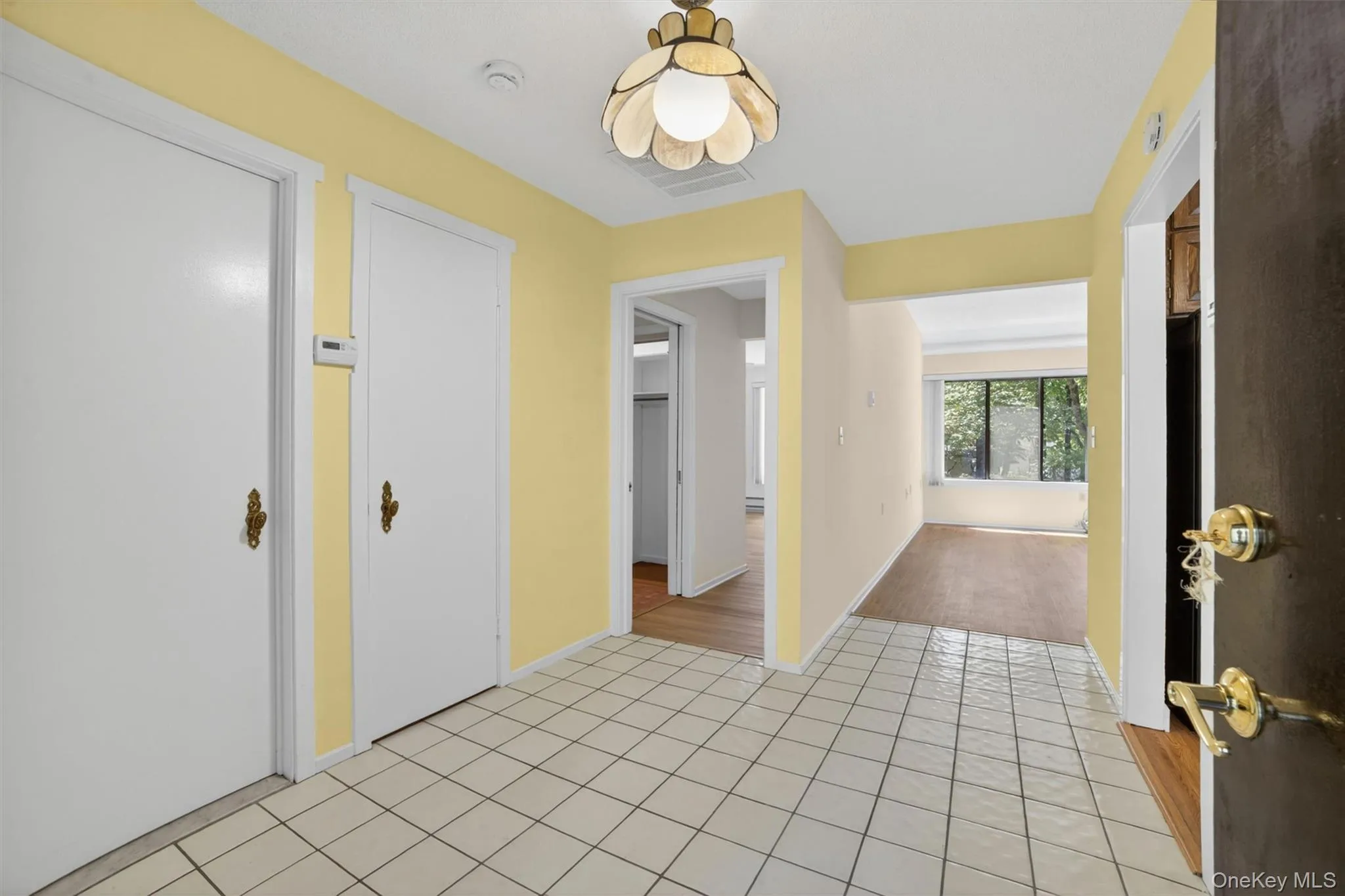 Entryway featuring square white ceramic tile flooring and a decorative semi-flush mount light fixture Entryway featuring square white ceramic tile flooring and a decorative semi-flush mount light fixture