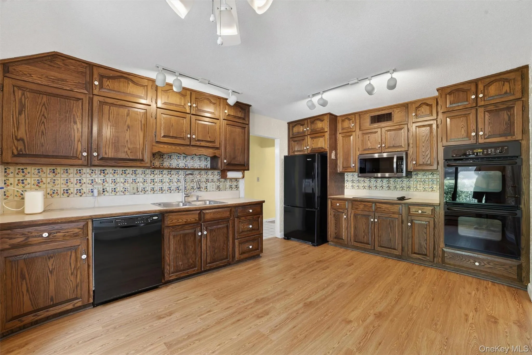 Kitchen featuring wood-finish flooring, extensive wood cabinetry, and a double-basin stainless steel sink Kitchen featuring wood-finish flooring, extensive wood cabinetry, and a double-basin stainless steel sink