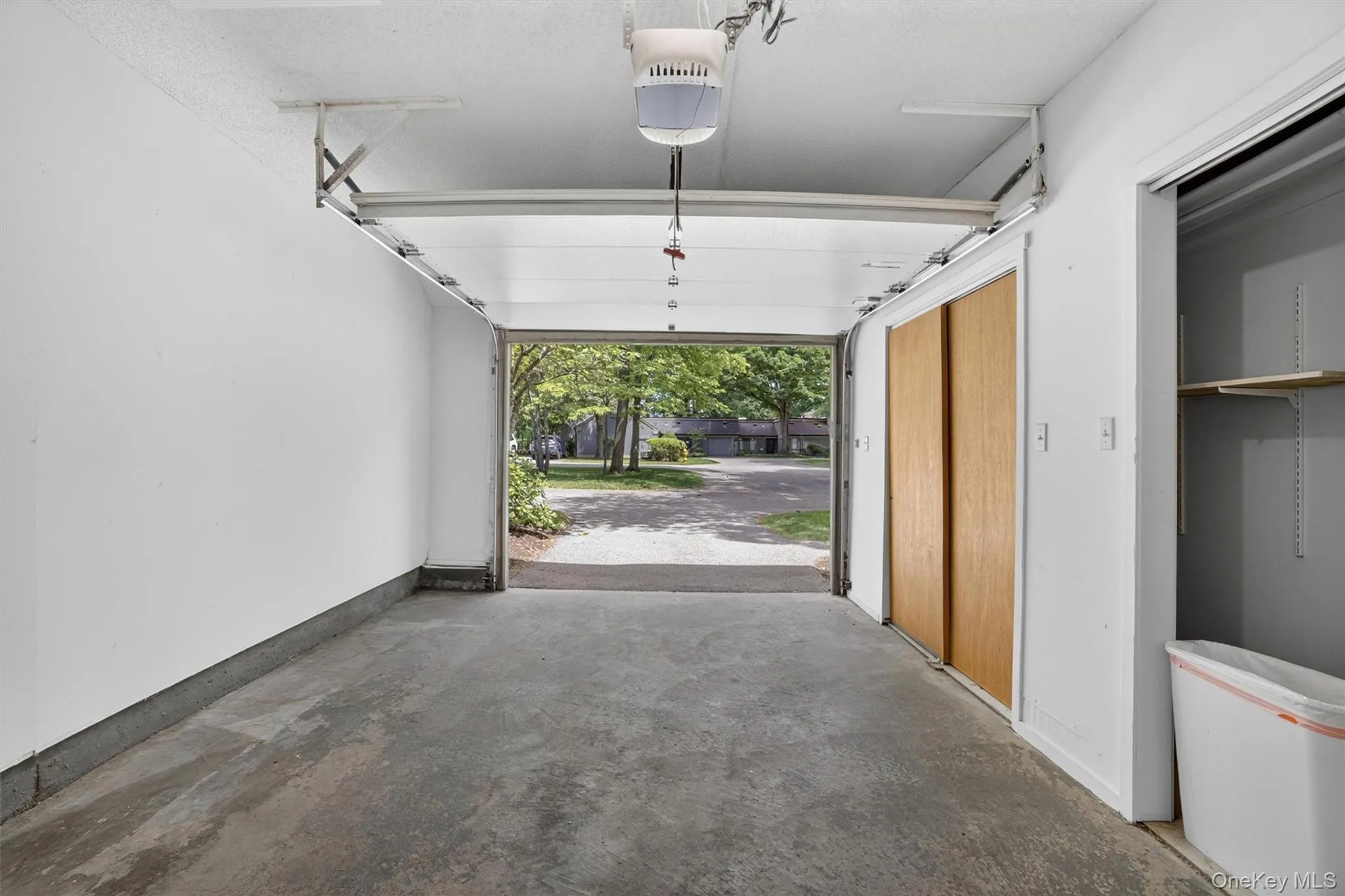 Attached garage with concrete flooring, automatic garage door opener, and a built-in storage closet with natural wood-finish sliding doors Attached garage with concrete flooring, automatic garage door opener, and a built-in storage closet with natural wood-finish sliding doors
