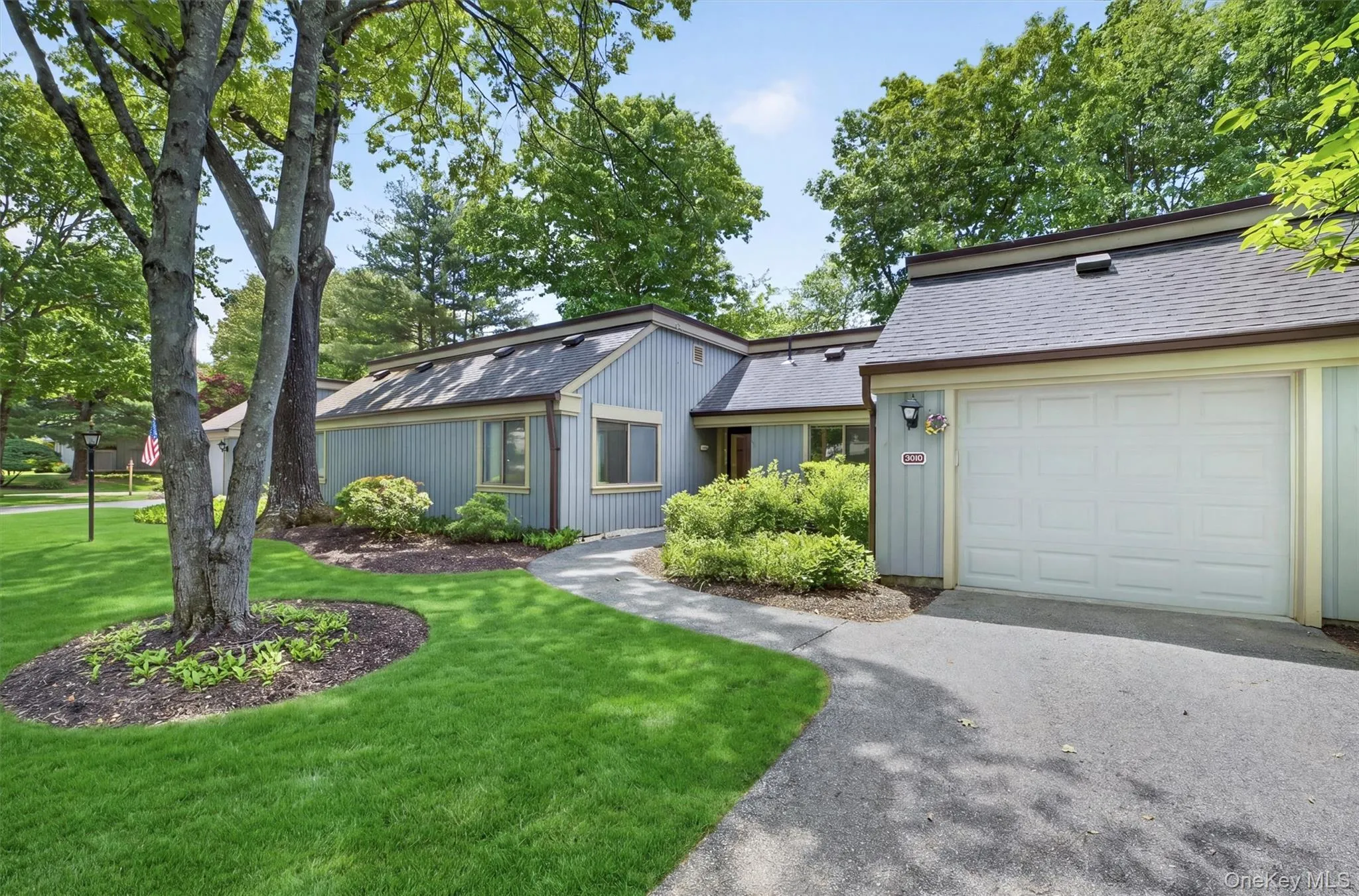 Front exterior featuring light blue siding, a dark asphalt shingle roof, and a white panel garage door Front exterior featuring light blue siding, a dark asphalt shingle roof, and a white panel garage door