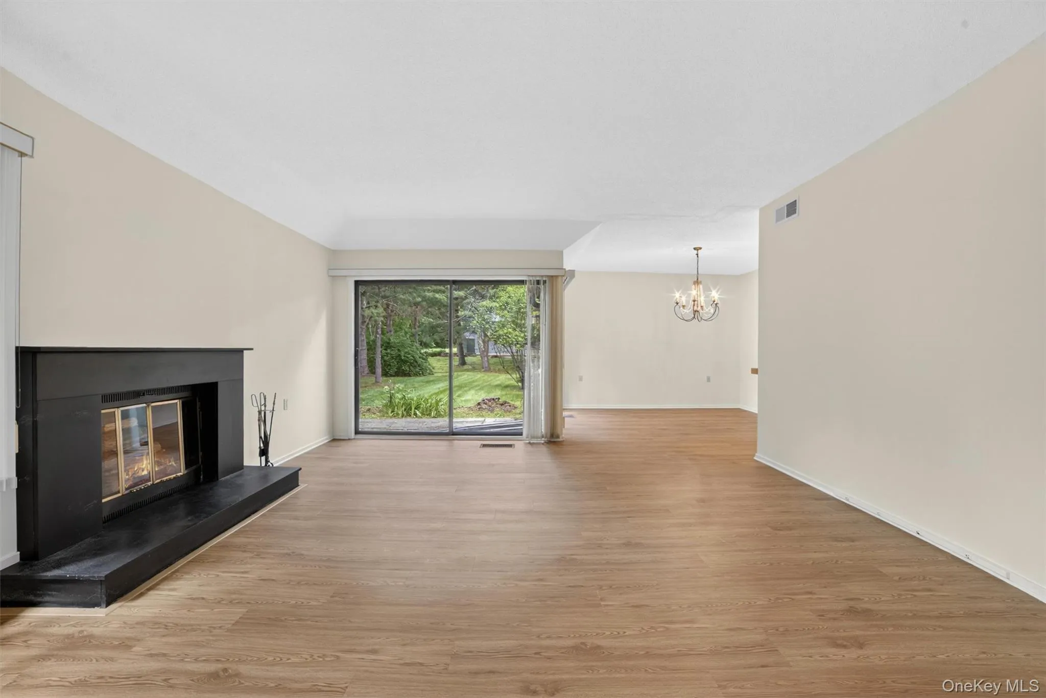 Living area featuring a black fireplace with hearth, wood-finish flooring, and sliding glass doors Living area featuring a black fireplace with hearth, wood-finish flooring, and sliding glass doors