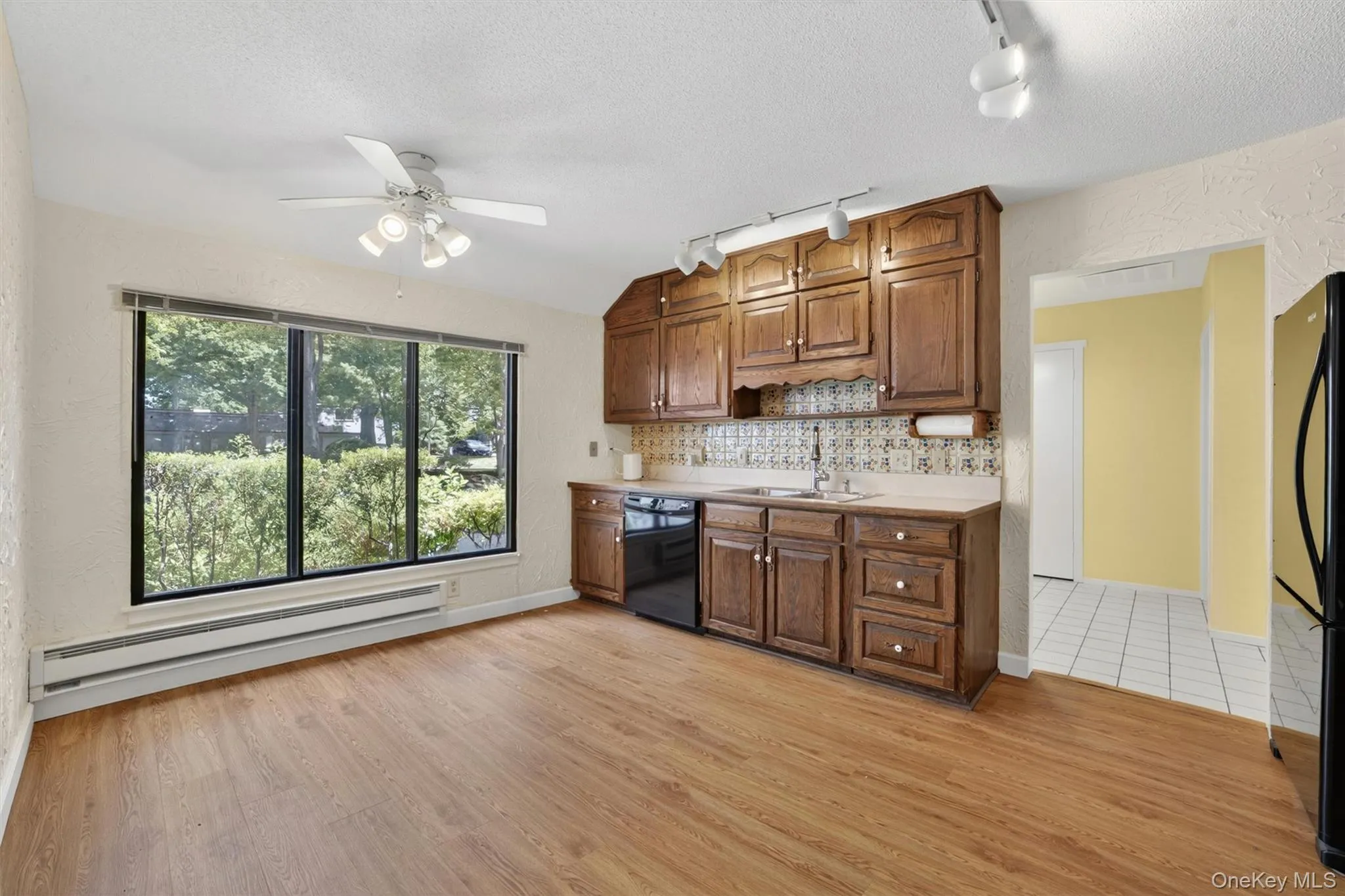 Kitchen area featuring rich wood cabinetry, a white countertop, and a patterned tile backsplash Kitchen area featuring rich wood cabinetry, a white countertop, and a patterned tile backsplash