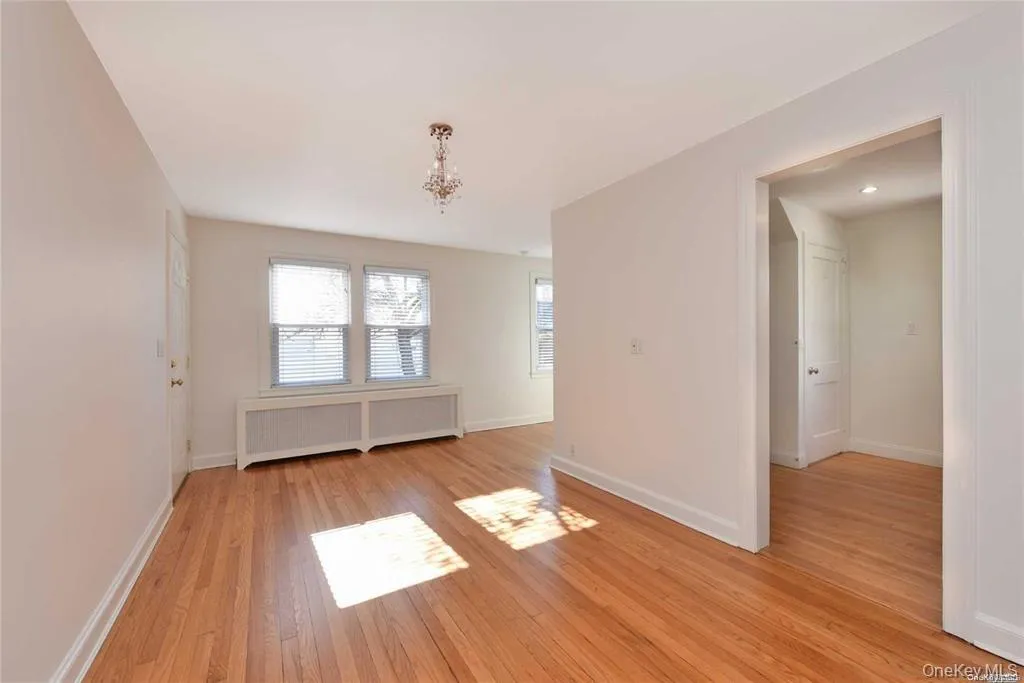 Spare room with radiator, light wood-style floors, and a chandelier Spare room with radiator, light wood-style floors, and a chandelier