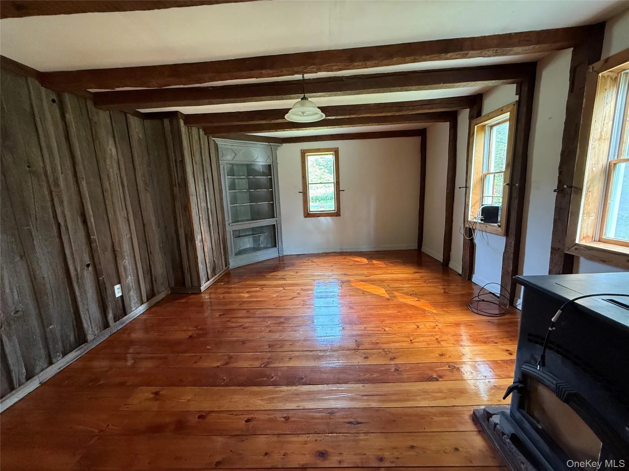 Unfurnished dining area with hardwood / wood-style floors, wood walls, and beamed ceiling Unfurnished dining area with hardwood / wood-style floors, wood walls, and beamed ceiling