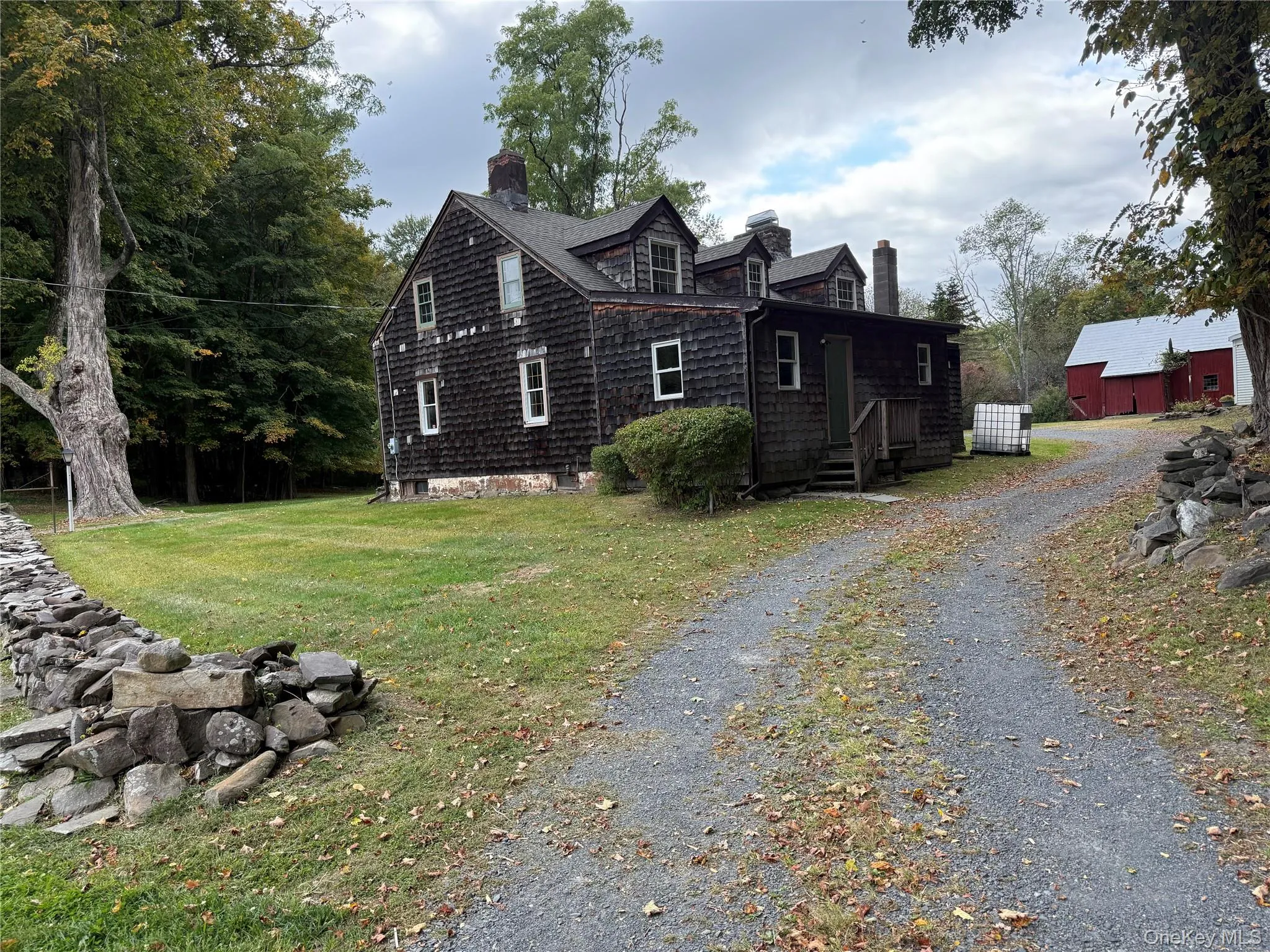 View of side of home with a chimney, driveway, a lawn, and an outdoor structure View of side of home with a chimney, driveway, a lawn, and an outdoor structure